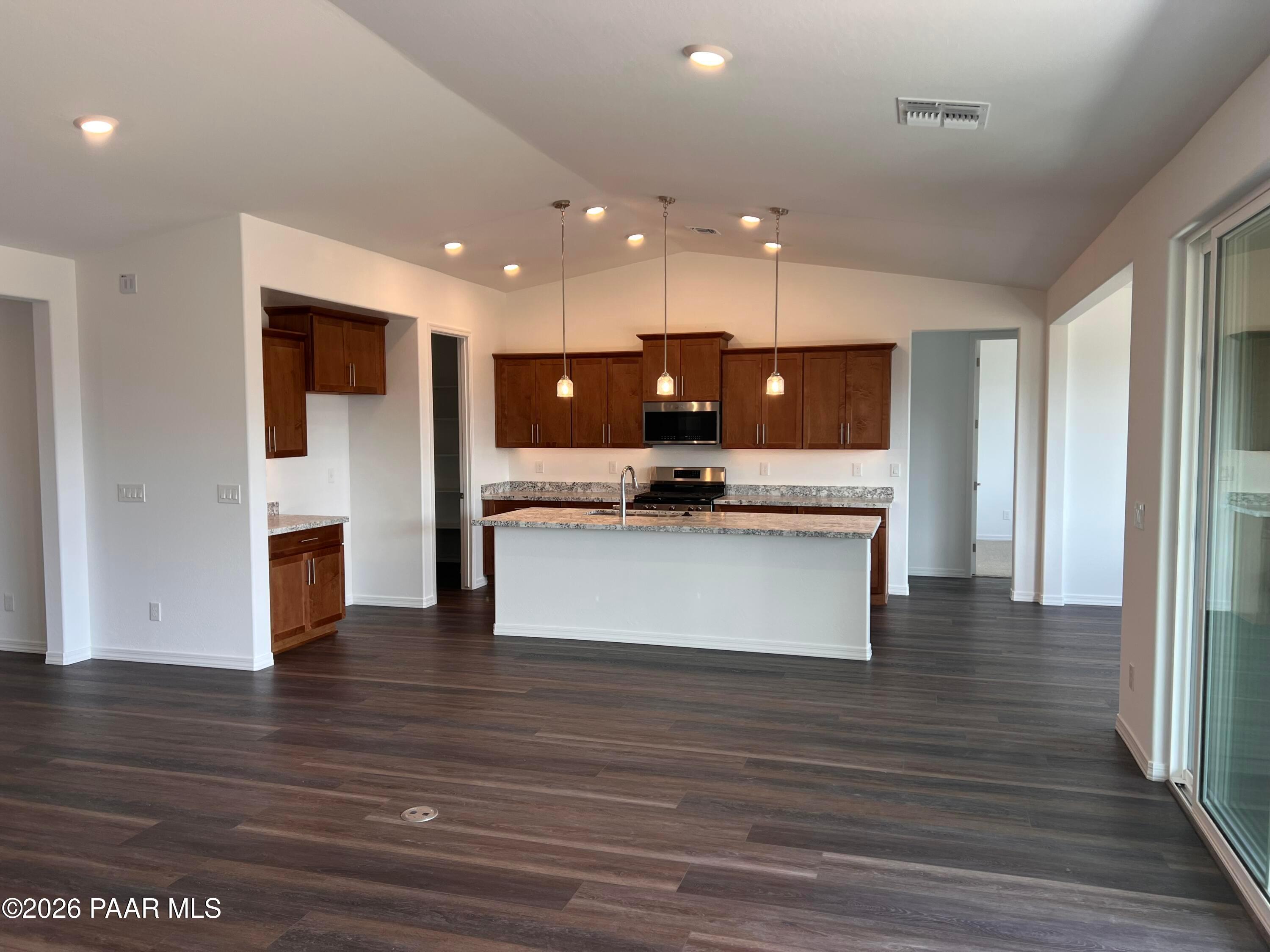 Modern open-concept kitchen with large white island, wood cabinets, stainless appliances in Davidson Homes The Monarch A, Prescott, AZ