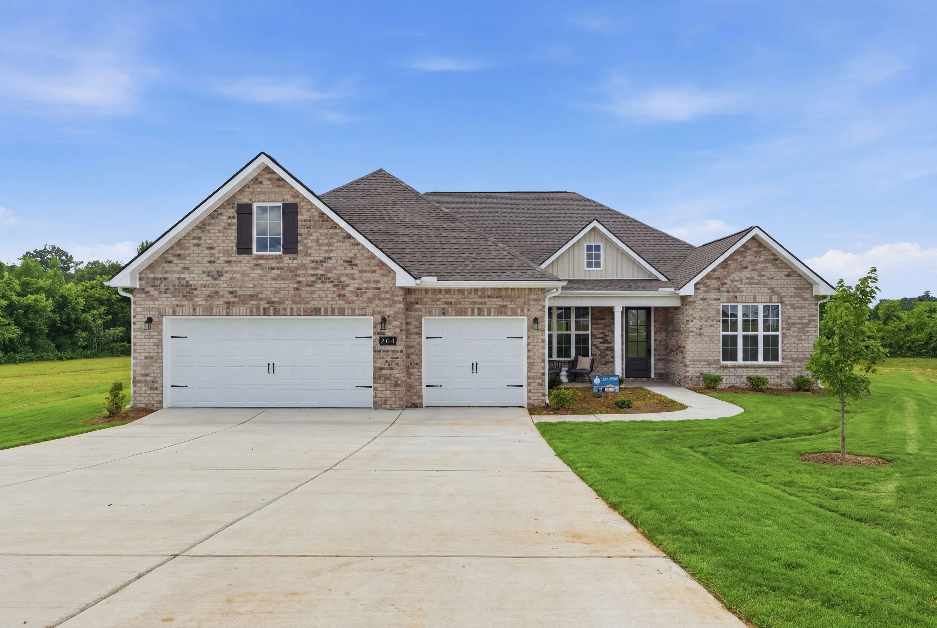 Brick exterior of a Davidson Homes house at Riverton Preserve in Huntsville, Alabama with a three-car garage and lawn.