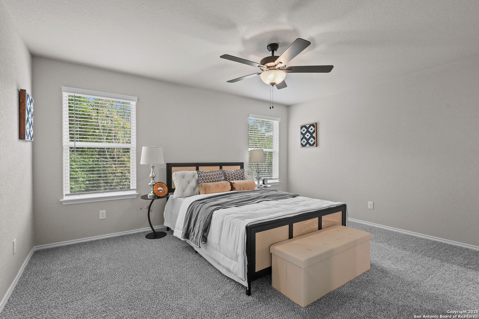 Cozy bedroom with black-framed king bed, ceiling fan, and window views in Davidson Homes The Charlotte B, San Antonio, Texas