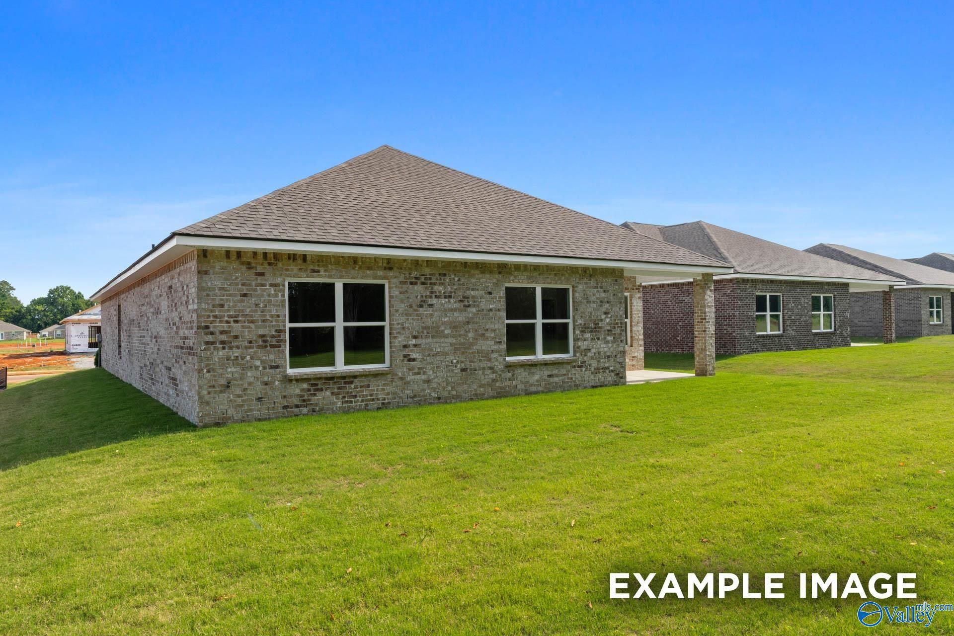 Single-story brick home with gabled roof, double windows, attached carport, and lush green yard in The Highlands, Arab, Alabama