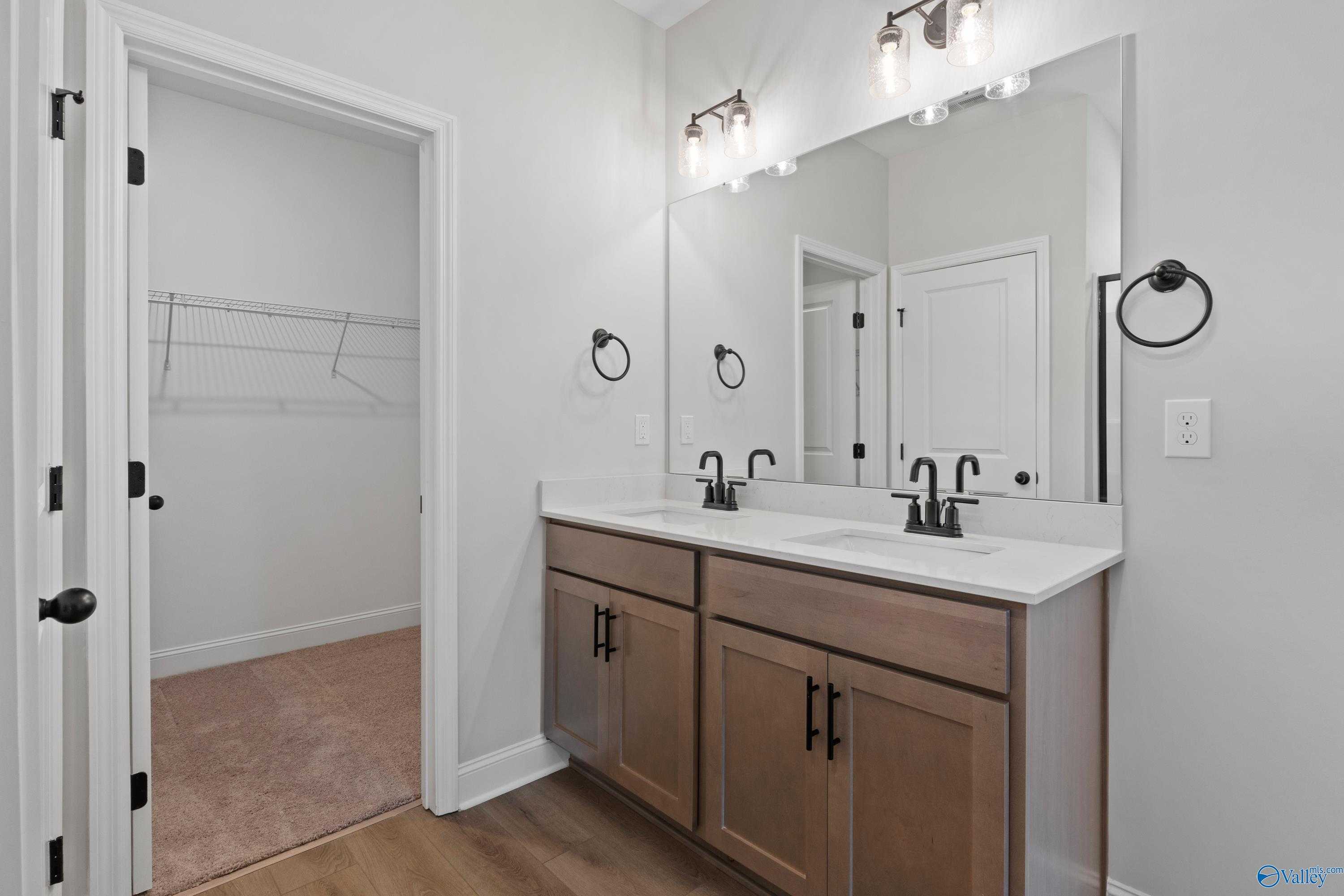 Modern master bathroom with double vanity, large mirrors, and open walk-in closet in Davidson Homes The Franklin C, Hazel Green, Alabama