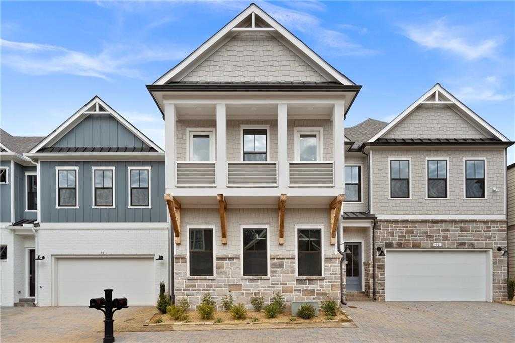Row of modern 2-story townhomes with shake siding, stone accents, and 3-car garages in The Village at Towne Lake, Woodstock, Georgia