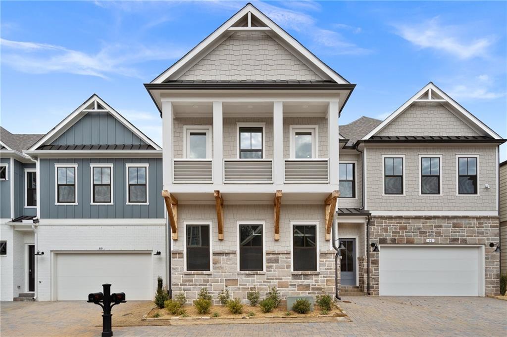 Row of modern 2-story townhomes with shake siding, stone accents, and 3-car garages in The Village at Towne Lake, Woodstock, Georgia