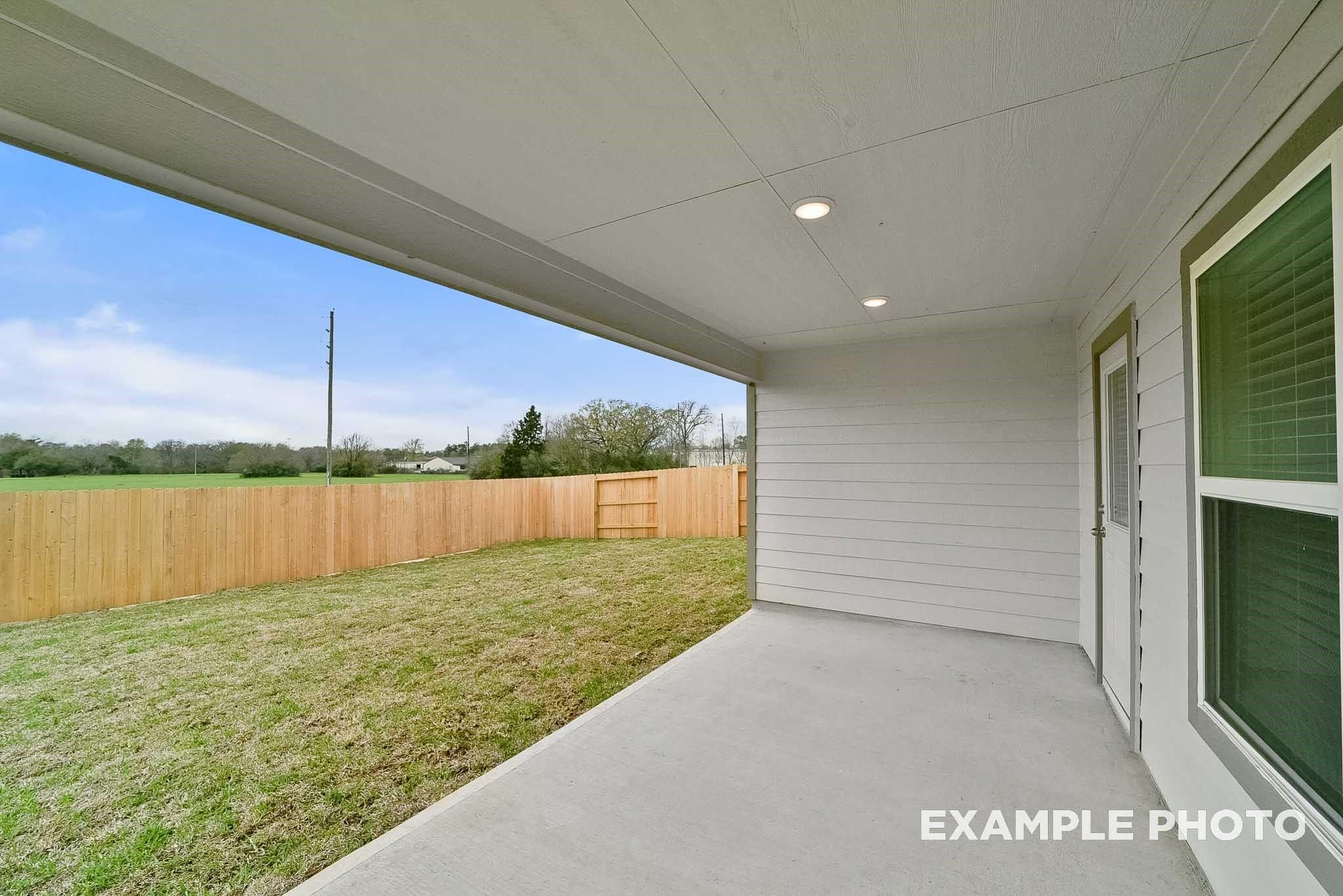 Covered patio with concrete floor and wooden fence overlooking lush backyard in Davidson Homes Tierra B, Emberly, Beasley, Texas