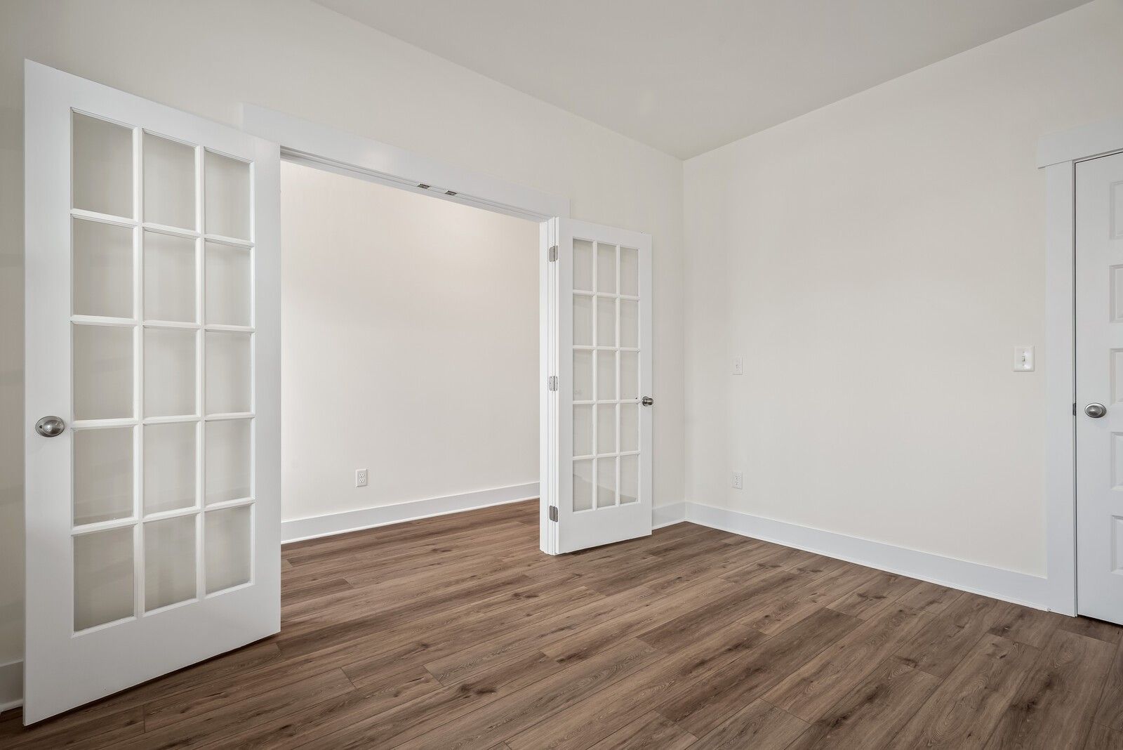 Open glass-paneled French doors in airy white room with hardwood floors, The Logan C by Davidson Homes, Gallatin, Tennessee