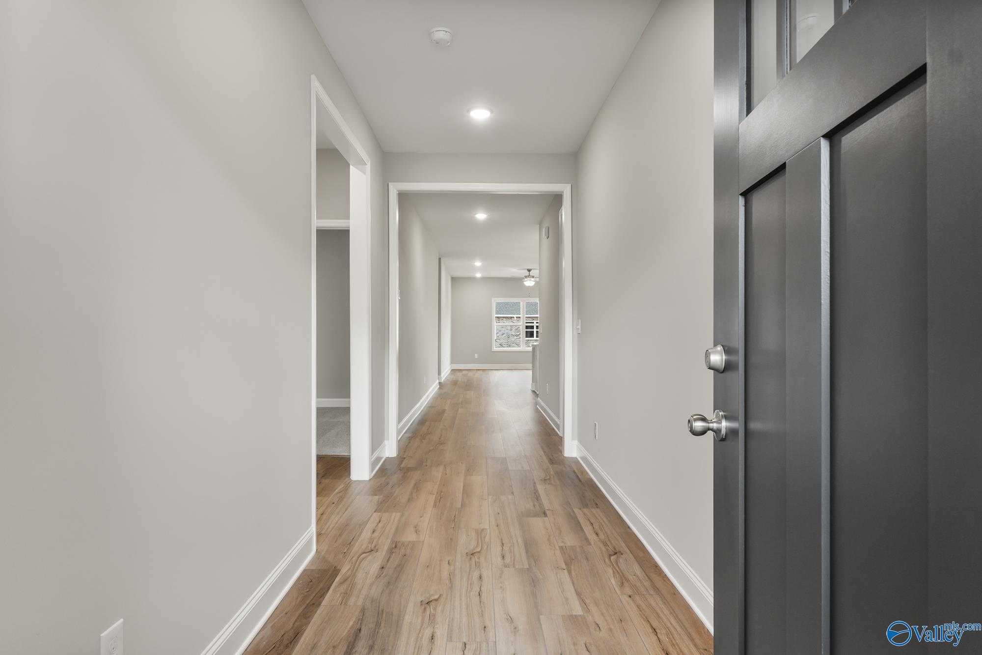 Elegant hallway with hardwood floors, neutral walls, and arched doorways in Davidson Homes The Daphne D, Athens AL