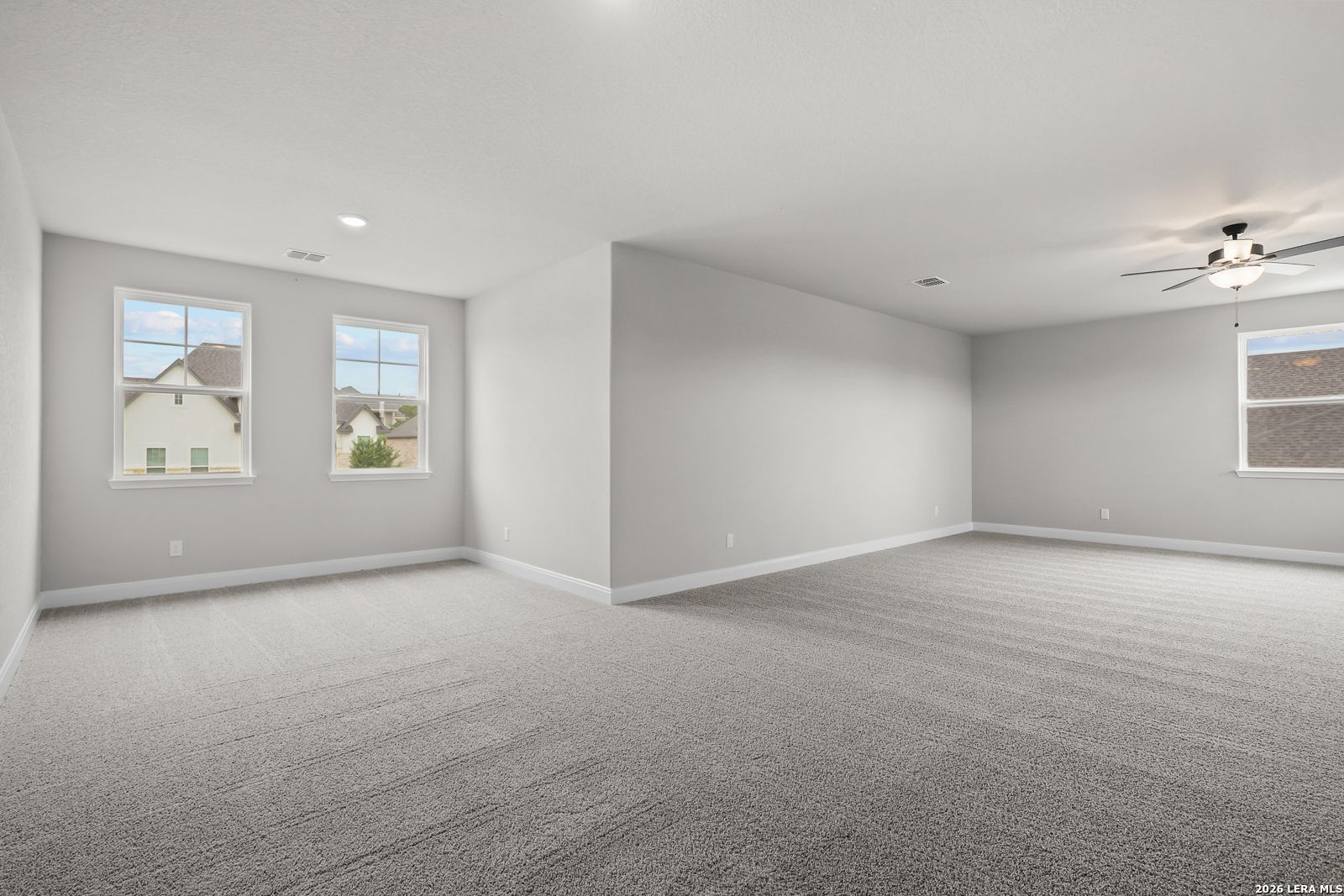 Spacious empty bedroom with gray walls, carpet, ceiling fan, and neighborhood views in Davidson Homes The Belmont H, Castroville, Texas