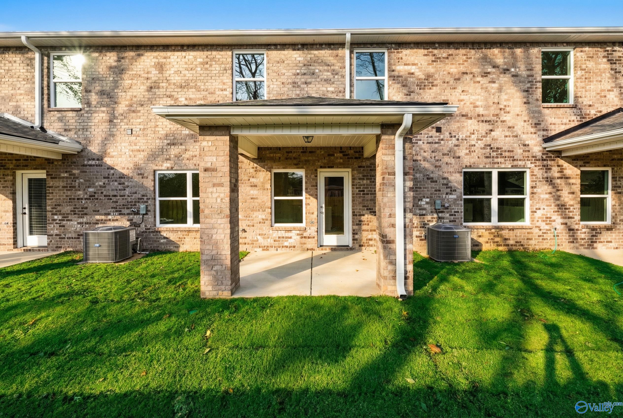 Two-story brick home with covered front porch, white door, and green lawn in Pavilion, Huntsville, Alabama - Davidson Homes Camden B
