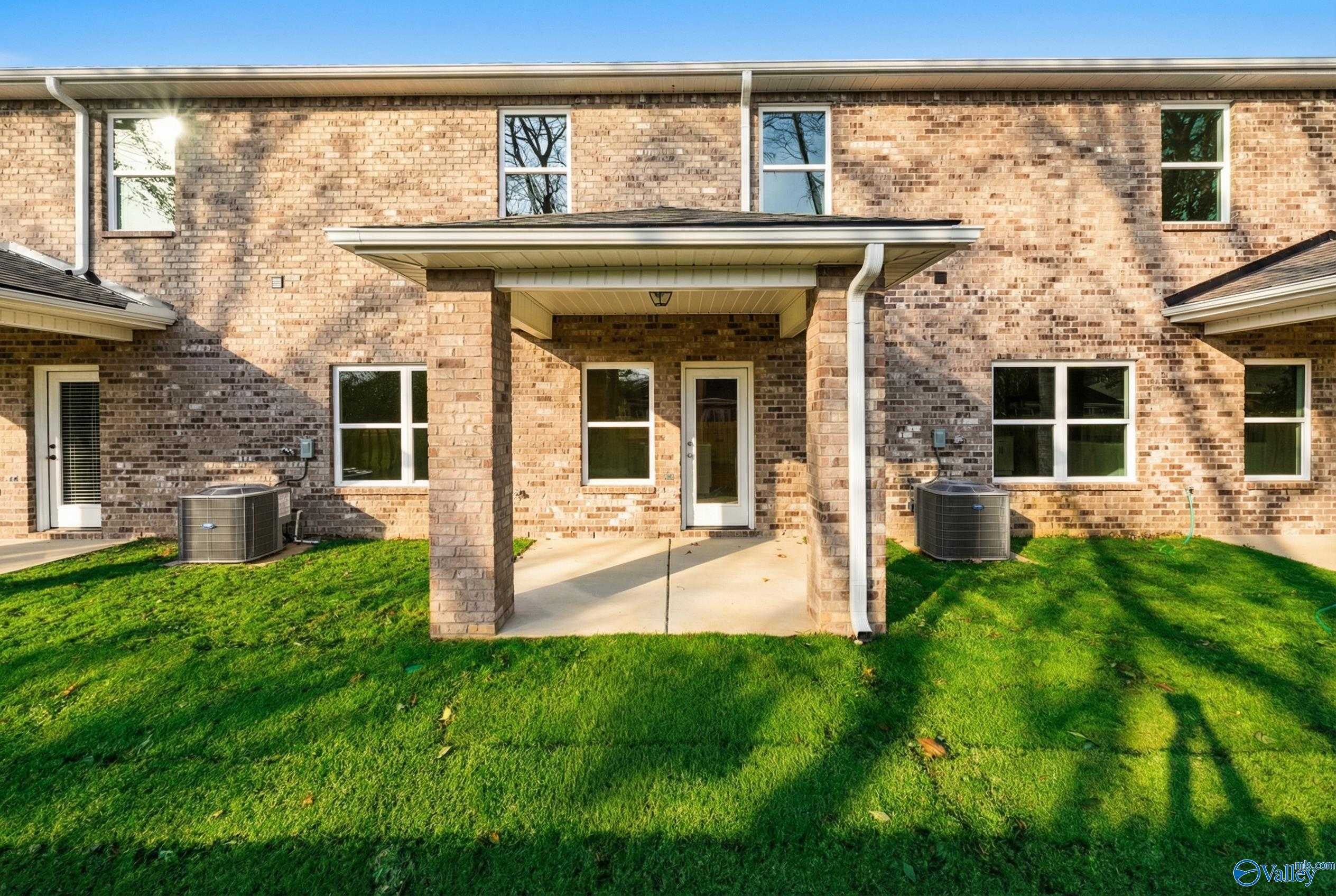 Two-story brick home with covered front porch, white door, and green lawn in Pavilion, Huntsville, Alabama - Davidson Homes Camden B