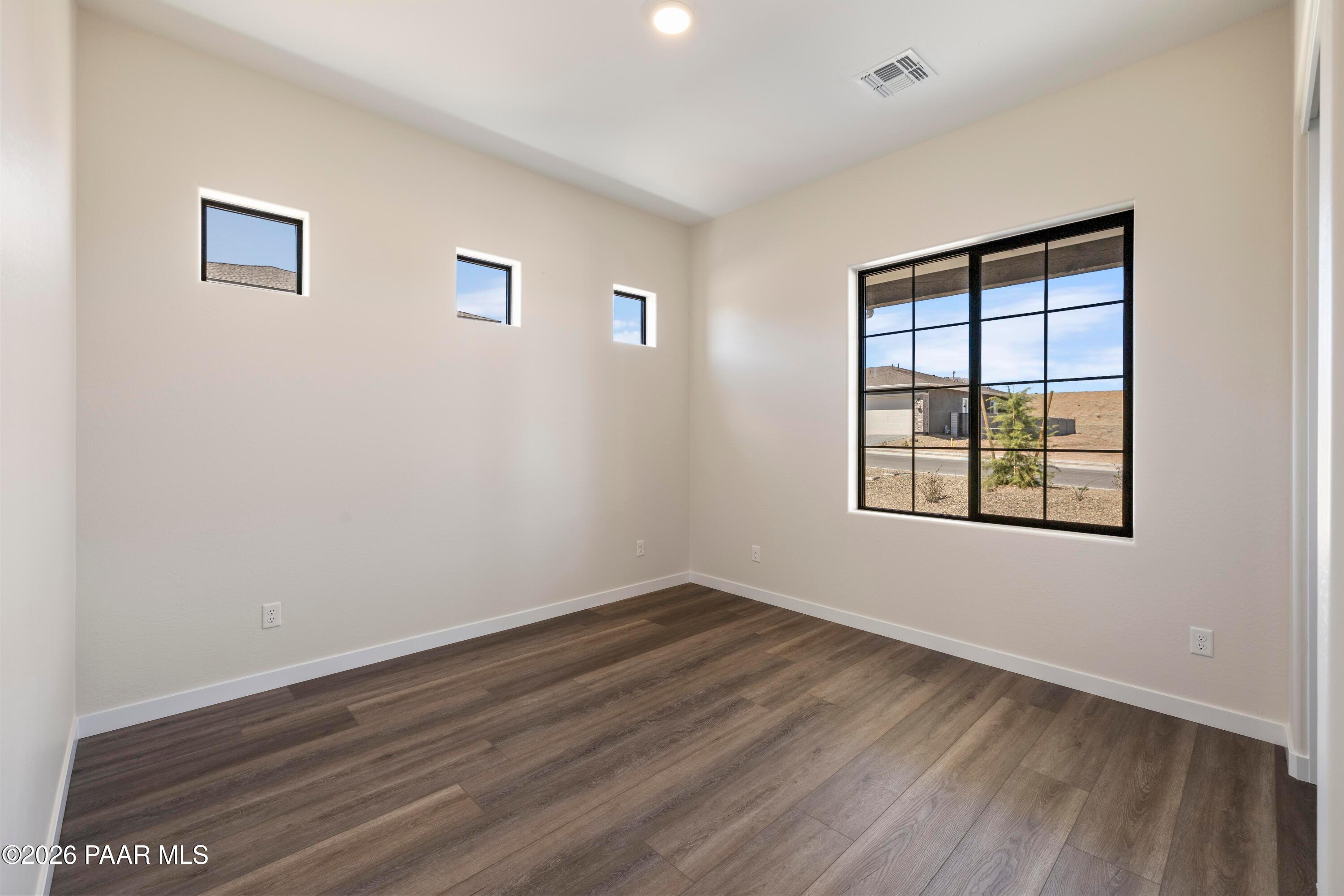 Bright bedroom with clerestory windows and desert view through large grid window in Davidson Homes Soleil E, Prescott AZ