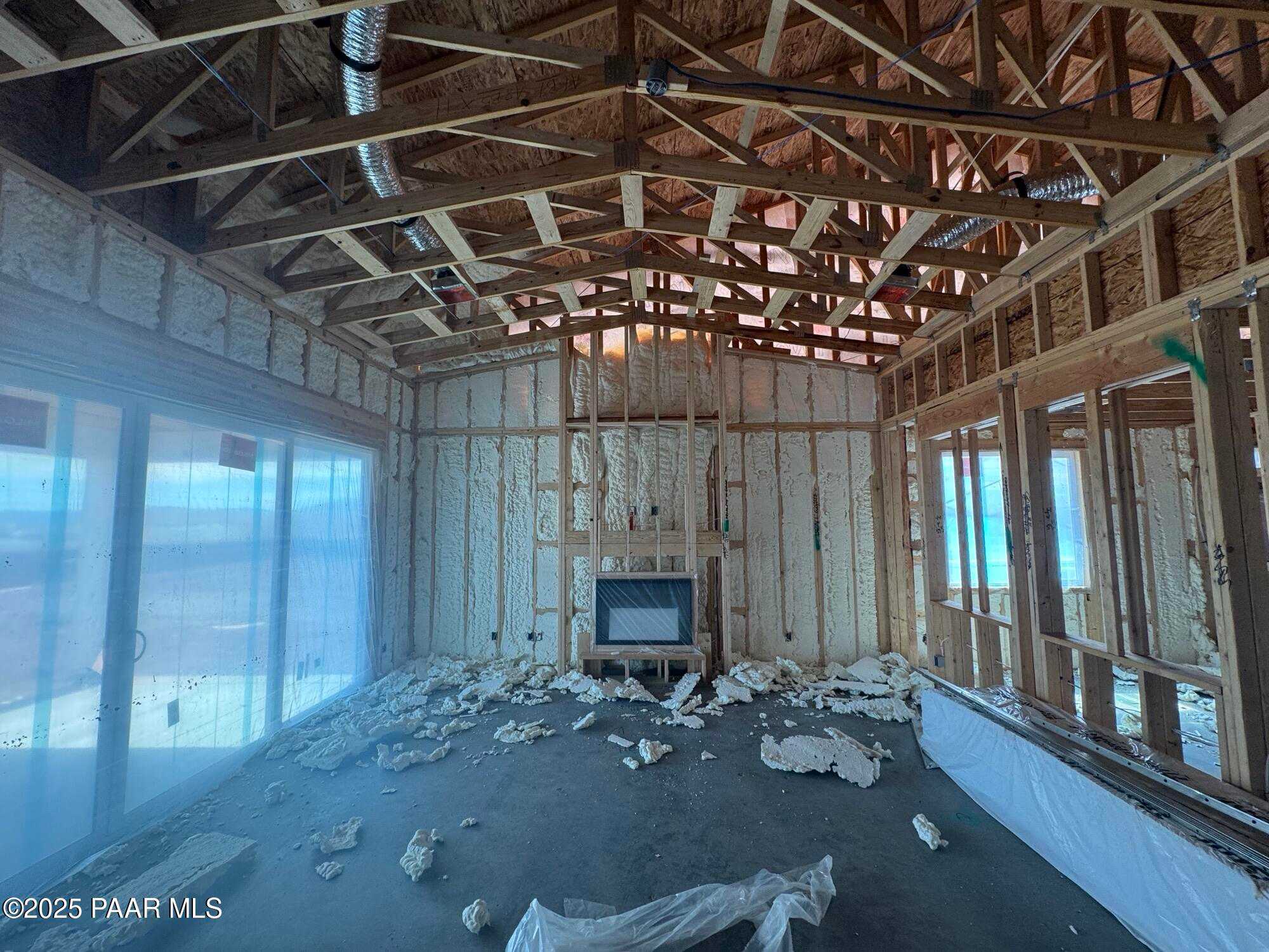 Exposed wooden beam ceiling, gas fireplace, and large sliding doors in great room of The Sunrise A home, Evermore Homes, Prescott Valley, Arizona