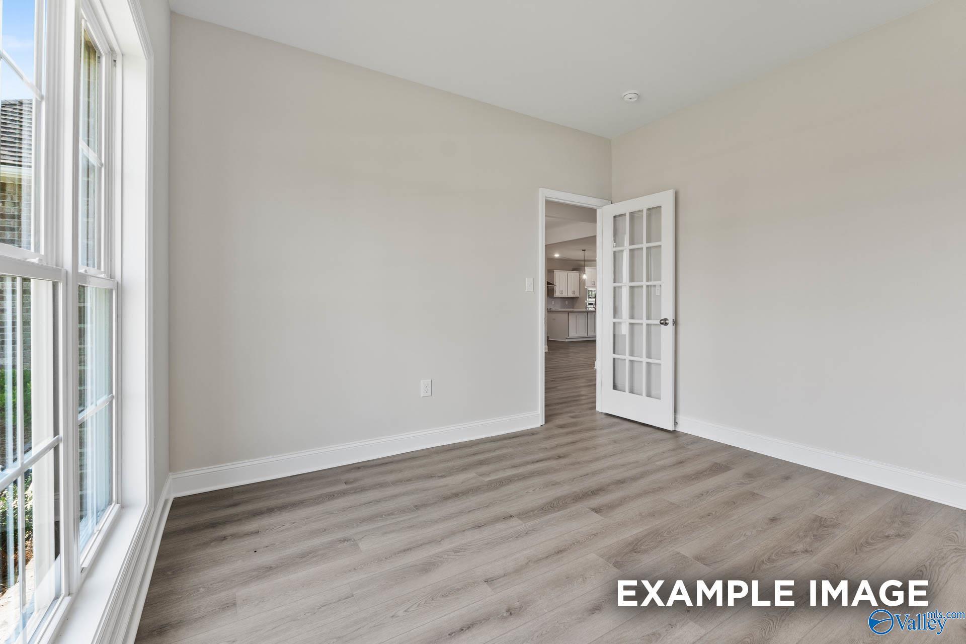Spacious dining room with luxury vinyl plank flooring, French doors to kitchen, and large windows in Davidson Homes The Finleigh, Huntsville, AL