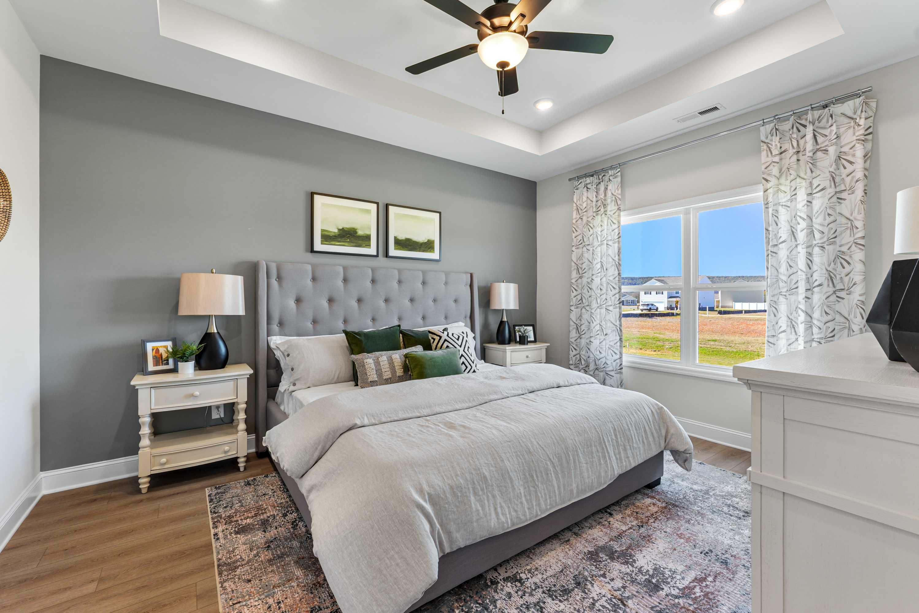 Spacious master bedroom in Ramsay Cove, Owens Cross Roads AL with king bed, gray walls, ceiling fan, and field view