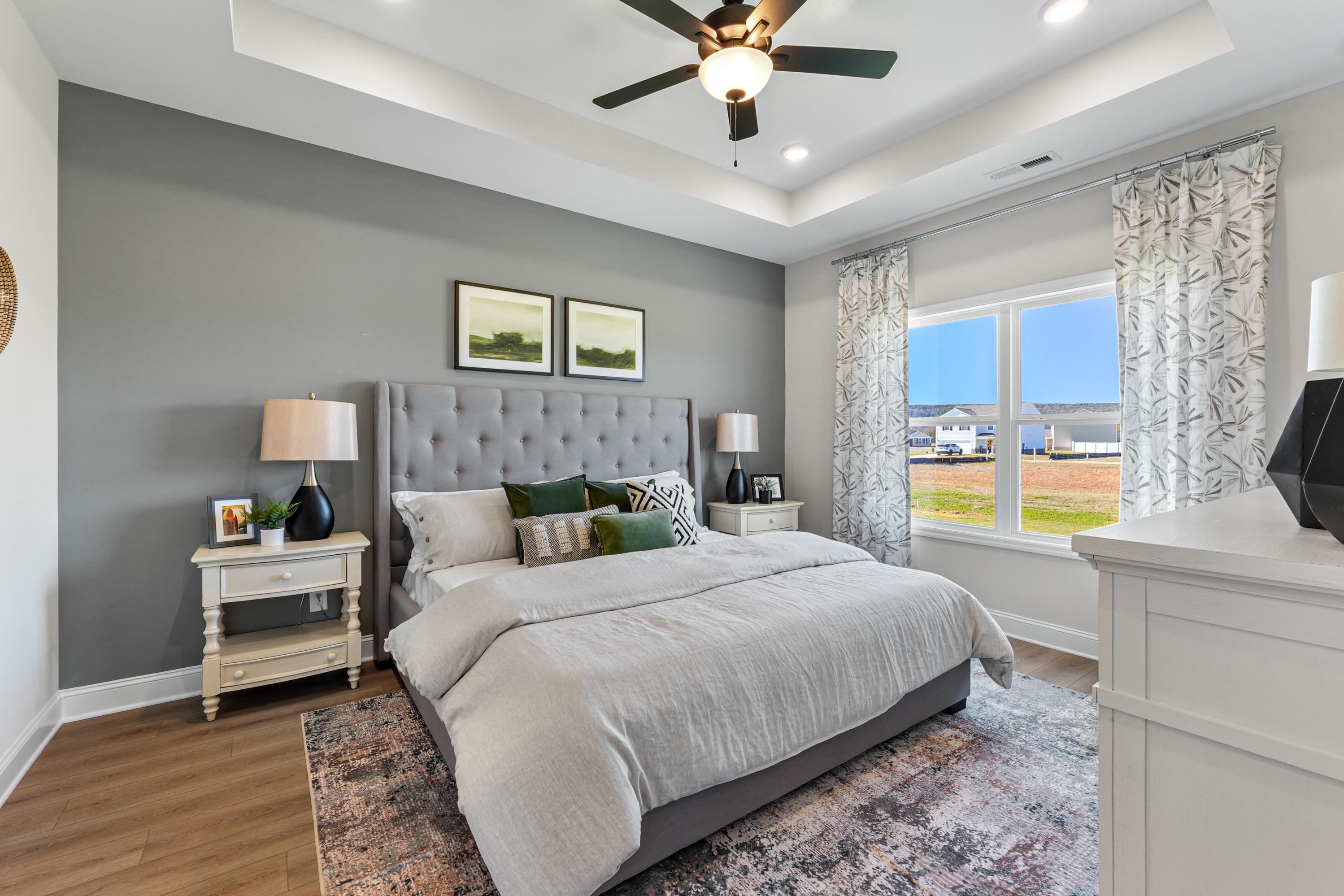 Spacious master bedroom in Ramsay Cove, Owens Cross Roads AL with king bed, gray walls, ceiling fan, and field view