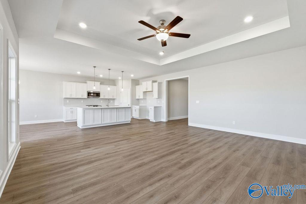 Modern open kitchen with white cabinets, large island, pendant lights, and ceiling fan in Davidson Homes The Harrison, Hartselle