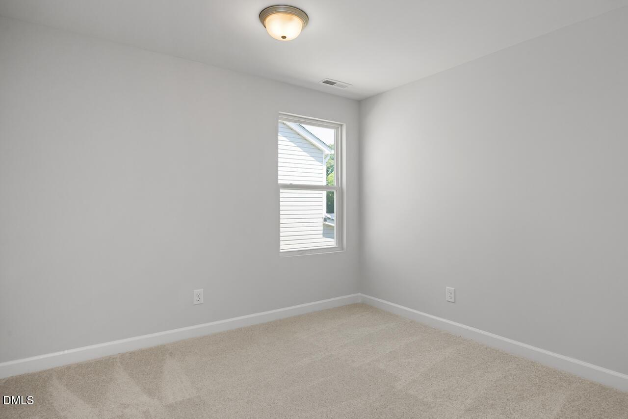 Bright, carpeted bedroom with neutral walls in The Adalynn A floor plan at Gregory Village in Lillington, North Carolina.