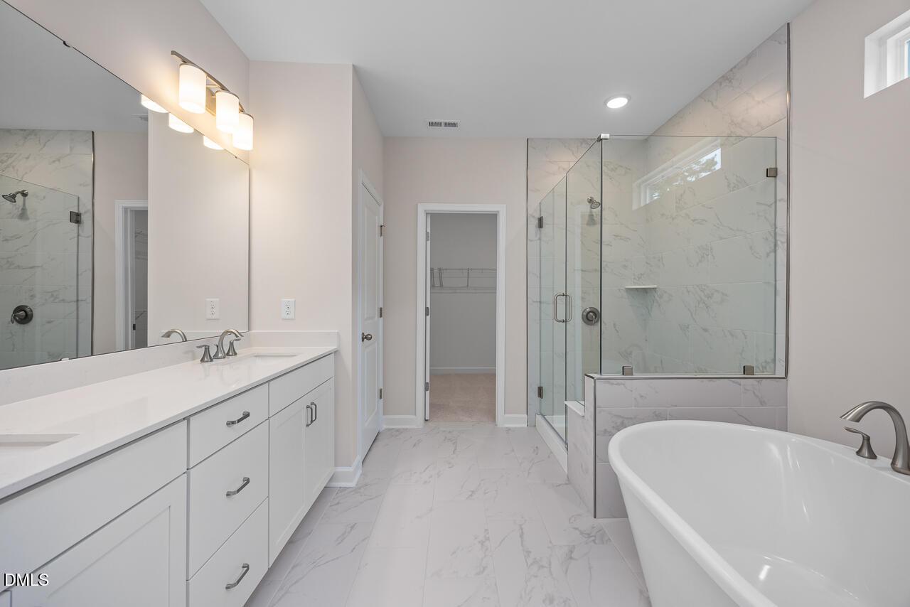 Modern primary bathroom with double vanity, soaking tub, and glass shower in Hickory II B plan at Woodland Crossing.