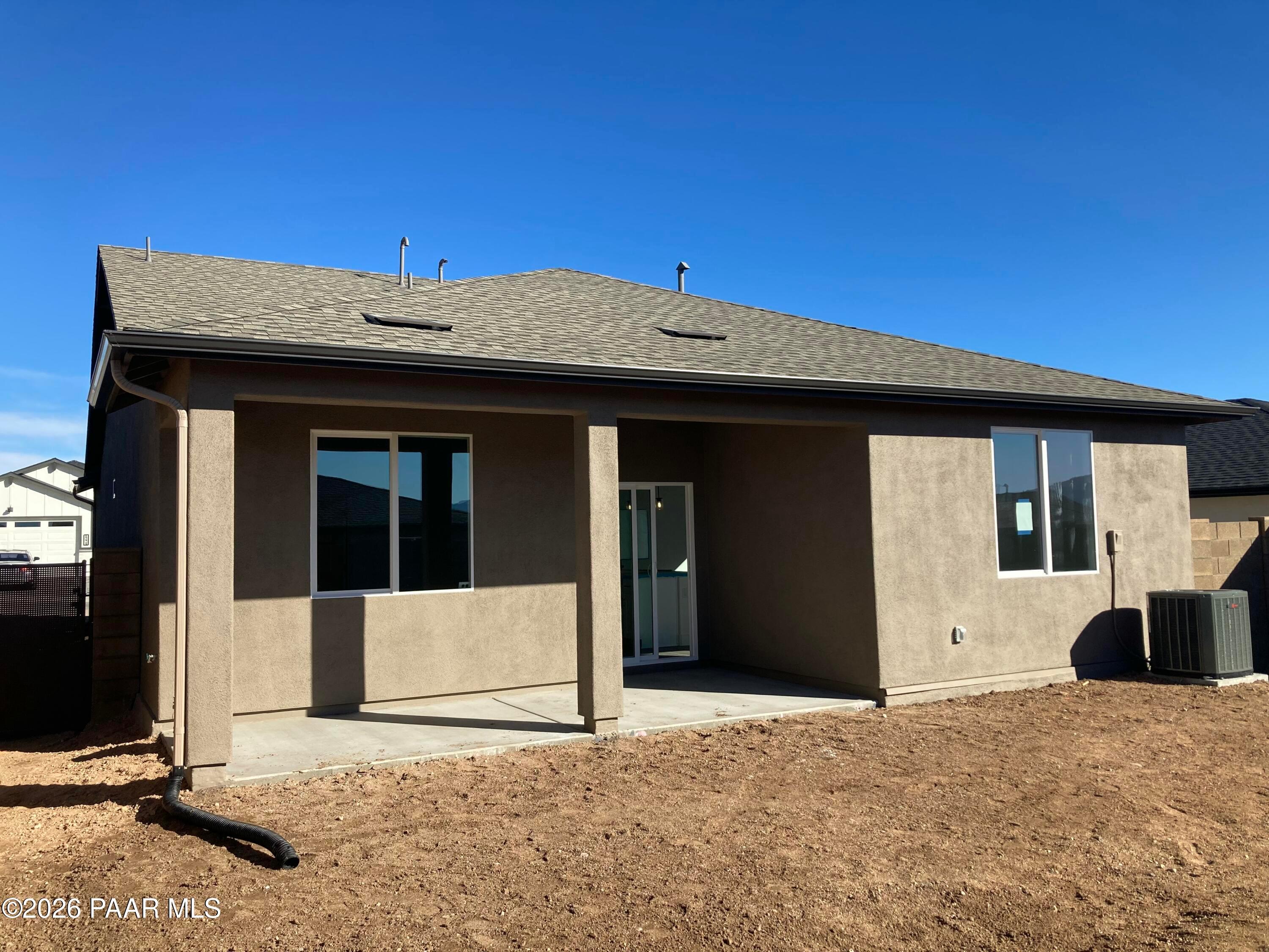 Rear view of single-story The Malibu C home by Davidson Homes with covered patio, sliding doors, and beige stucco in Prescott, Arizona