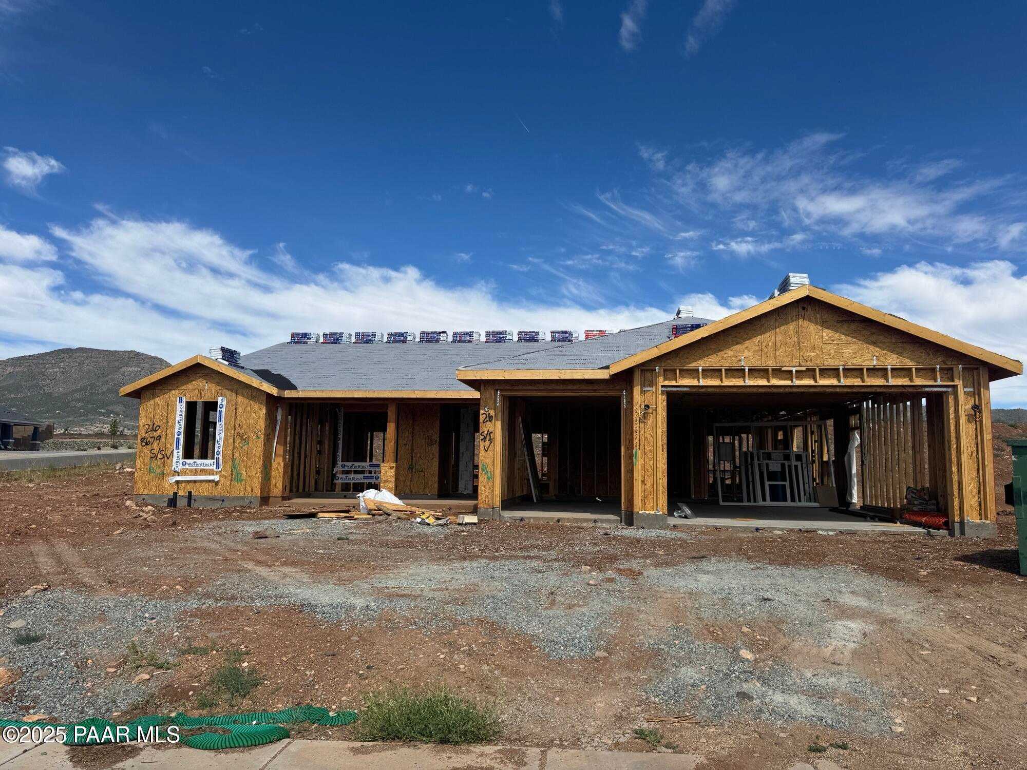 Under construction single-story home with wooden framing, 3-car garage, and mountain backdrop in Morningstar, Prescott Valley, Arizona by Evermore Homes