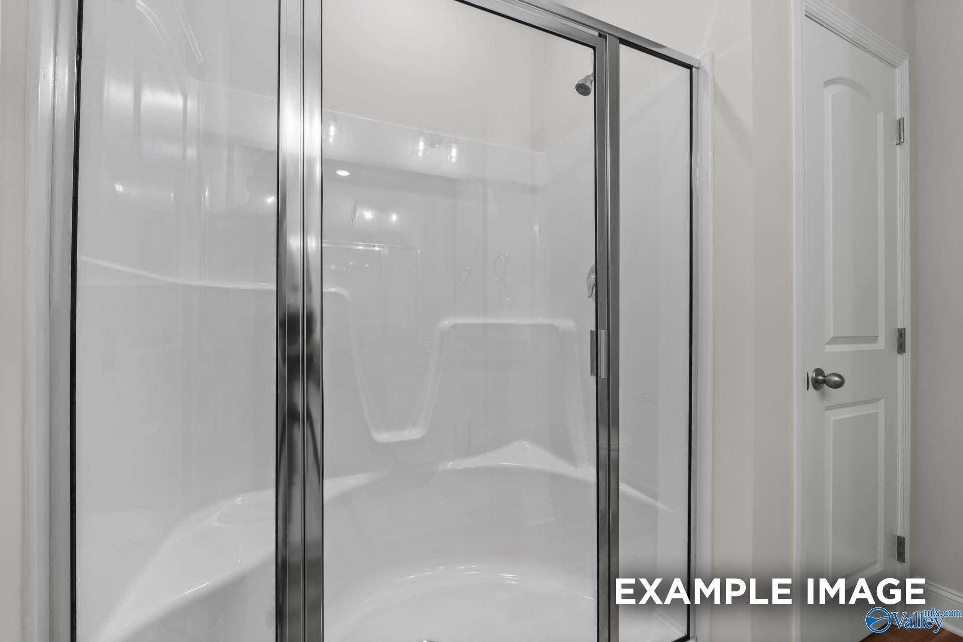 Framed glass walk-in shower with white subway tile in master bath of Davidson Homes The Butler in Toney, Alabama