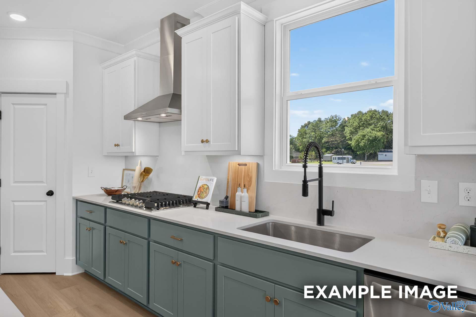 Modern kitchen with sage green cabinets, gas cooktop, and black faucet under window in Davidson Homes Ashport K, Hazel Green, AL