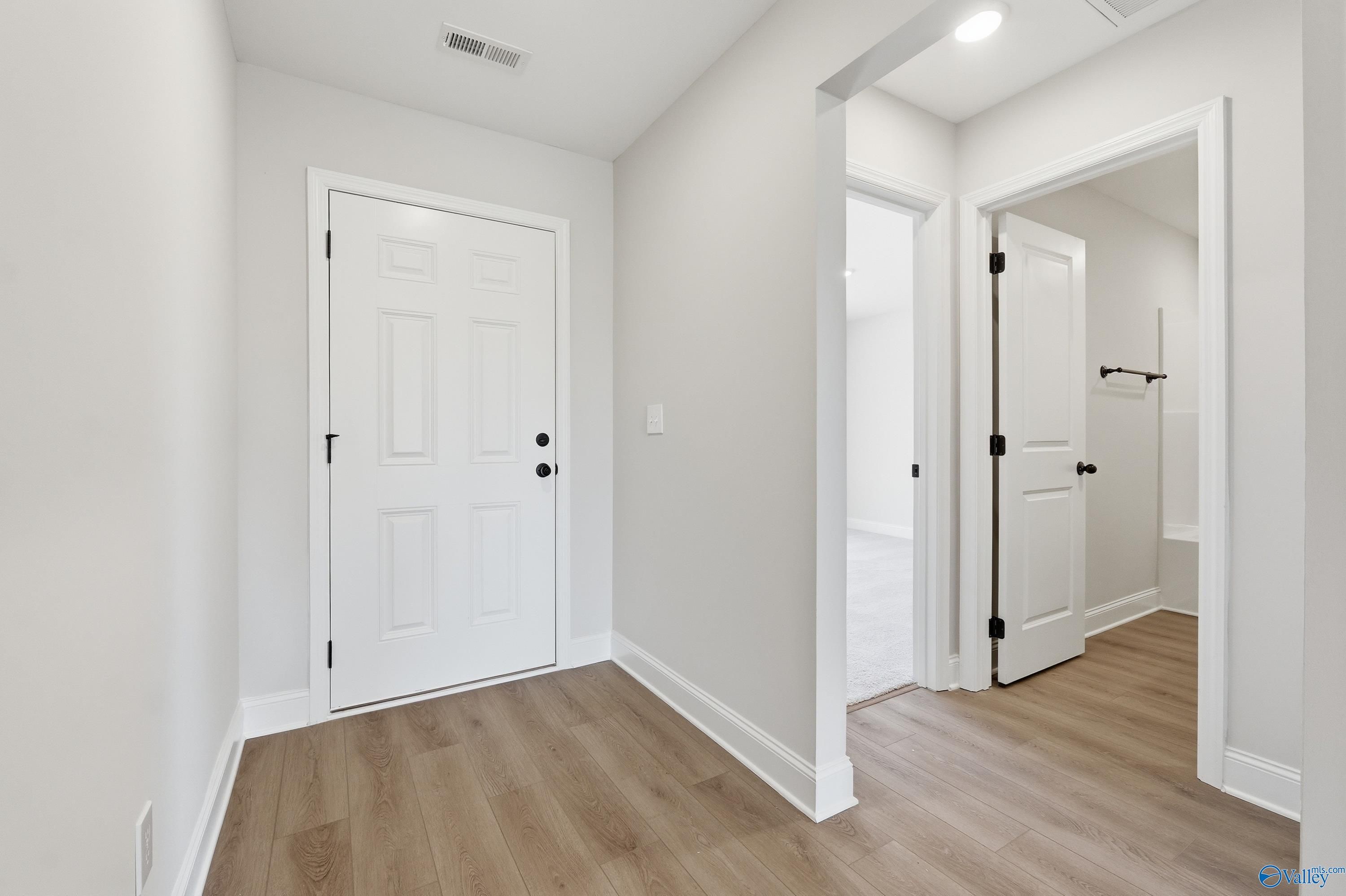 Bright hallway with white paneled doors, pocket door to bathroom, and light wood floors in 3-bedroom Davidson Homes The Franklin V, Athens AL