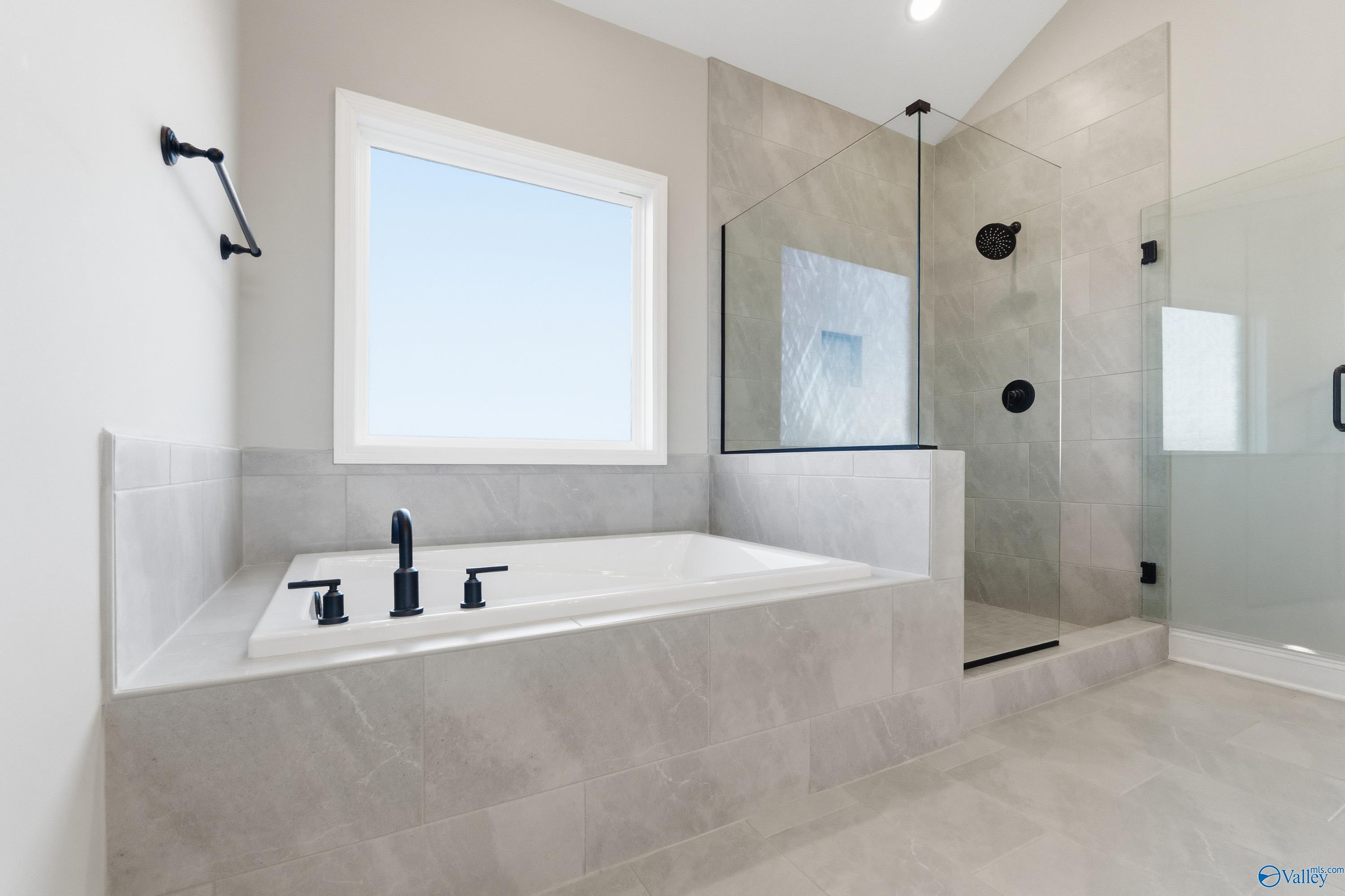 Luxurious master bathroom with freestanding tub, glass shower, and tiled accents in Davidson Homes The Finleigh, Meridianville, Alabama