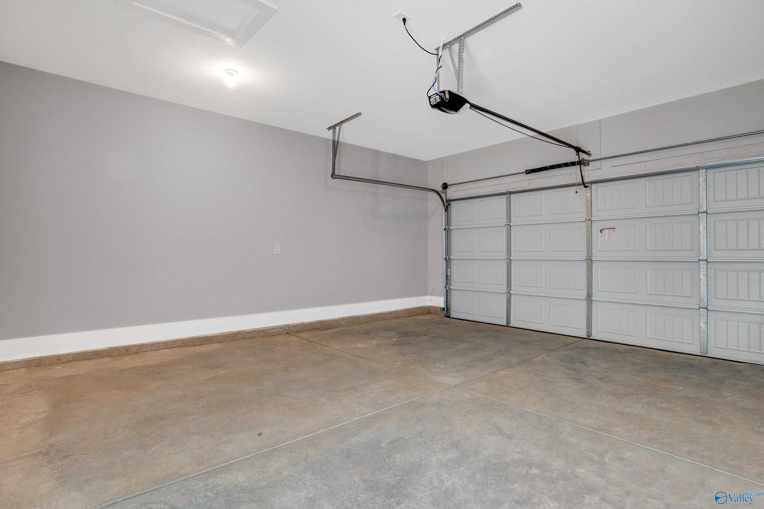 Spacious 2-car garage with gray walls, open door, and opener in Davidson Homes The Covington C, Decatur, Alabama