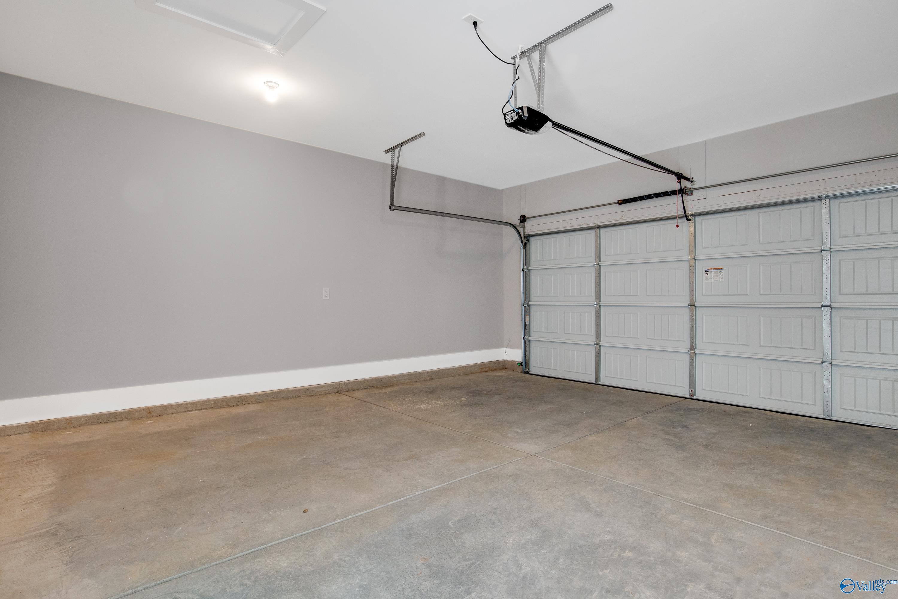 Spacious 2-car garage with gray walls, open door, and opener in Davidson Homes The Covington C, Decatur, Alabama