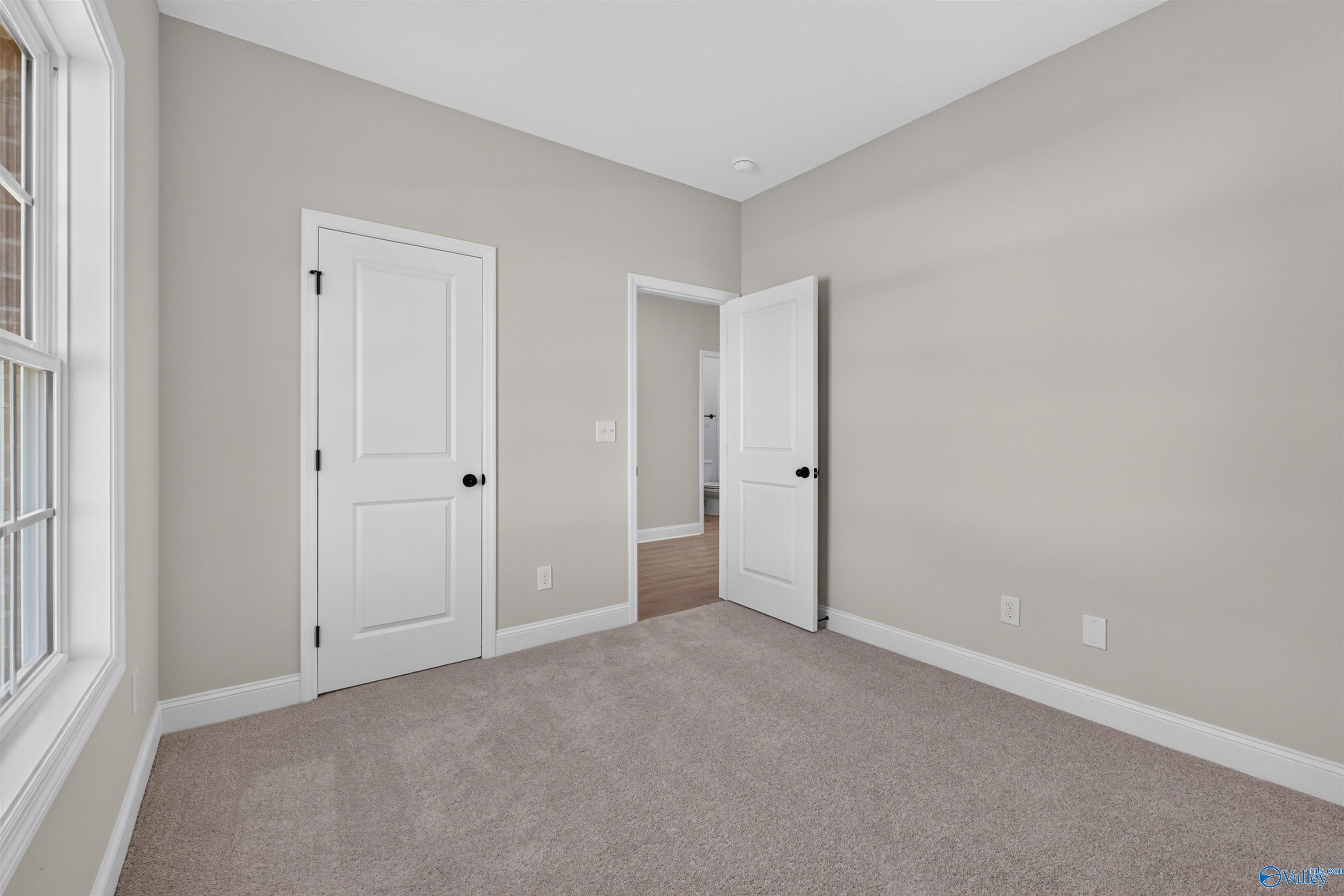 Bright carpeted bedroom with white doors and natural light in Davidson Homes The Butler floor plan, Clearview, Hazel Green, Alabama