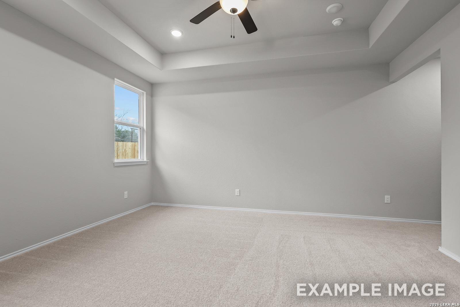 Spacious bedroom with carpeted flooring and tray ceiling in The Glenwood E floor plan by Davidson Homes, San Antonio.