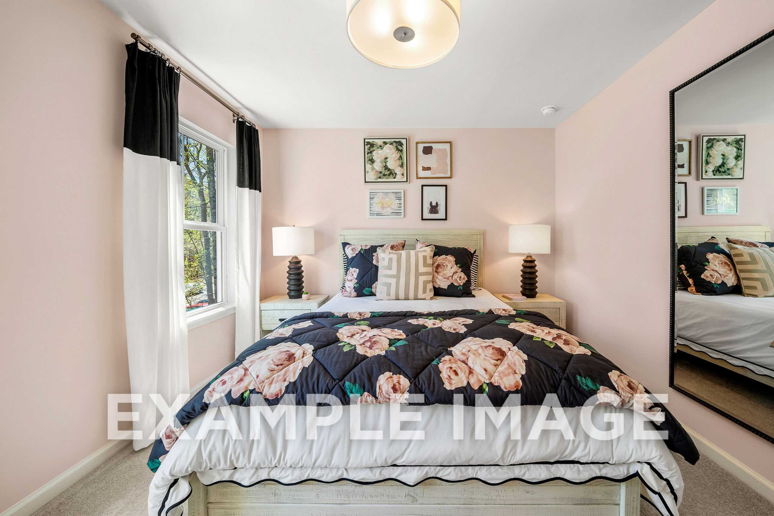 Cozy master bedroom in The Hickory A featuring floral black-and-pink duvet, sheer curtains, and mirrored wall