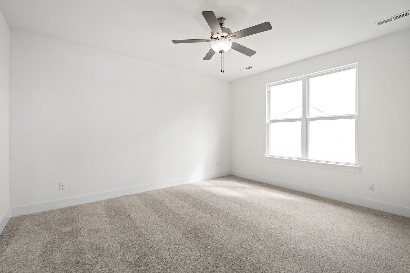 Bright secondary bedroom with ceiling fan, large window, and beige carpet in Davidson Homes The Ridgeport, Gallatin, TN