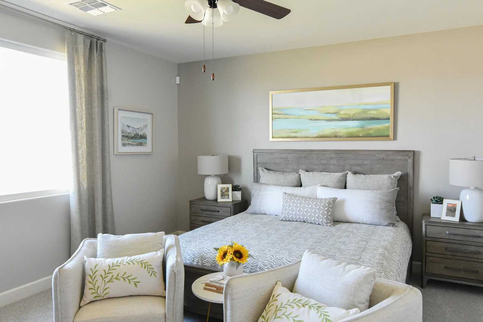 Serene master bedroom at Morningstar in Prescott Valley AZ featuring king bed, accent chairs, ceiling fan, and neutral decor