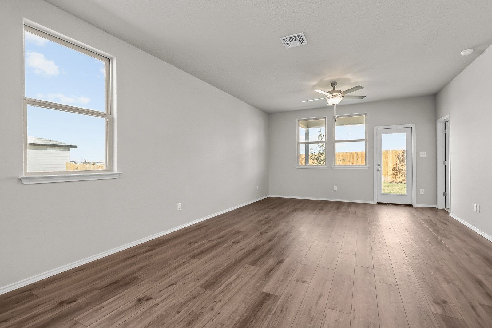 Bright, open-concept living area with wood-style flooring in The Frio G floor plan by Davidson Homes in Heartland, Texas.