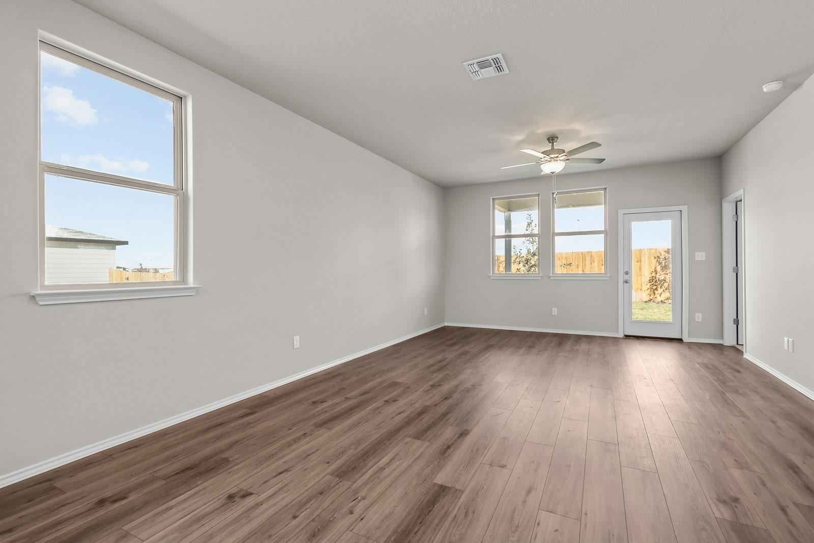Bright, open-concept living area with wood-style flooring in The Frio G floor plan by Davidson Homes in Heartland, Texas.