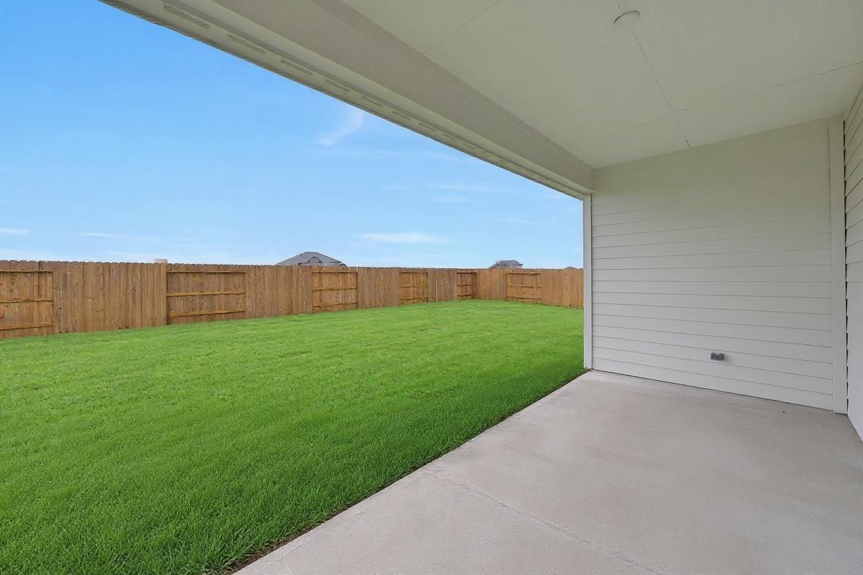 Covered patio overlooking lush green backyard with wooden fence in Davidson Homes The Edward A, Lago Mar, Texas City, Texas