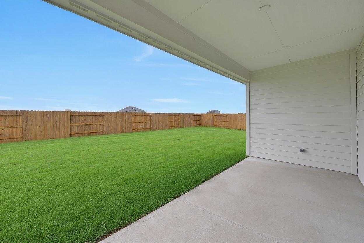 Covered patio overlooking lush green backyard with wooden fence in Davidson Homes The Edward A, Lago Mar, Texas City, Texas