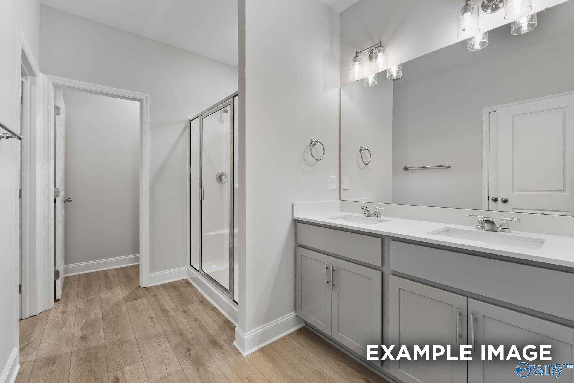 Elegant master bathroom with dual vanity, frameless glass shower, and neutral tones in Davidson Homes The Daphne C, New Market, AL