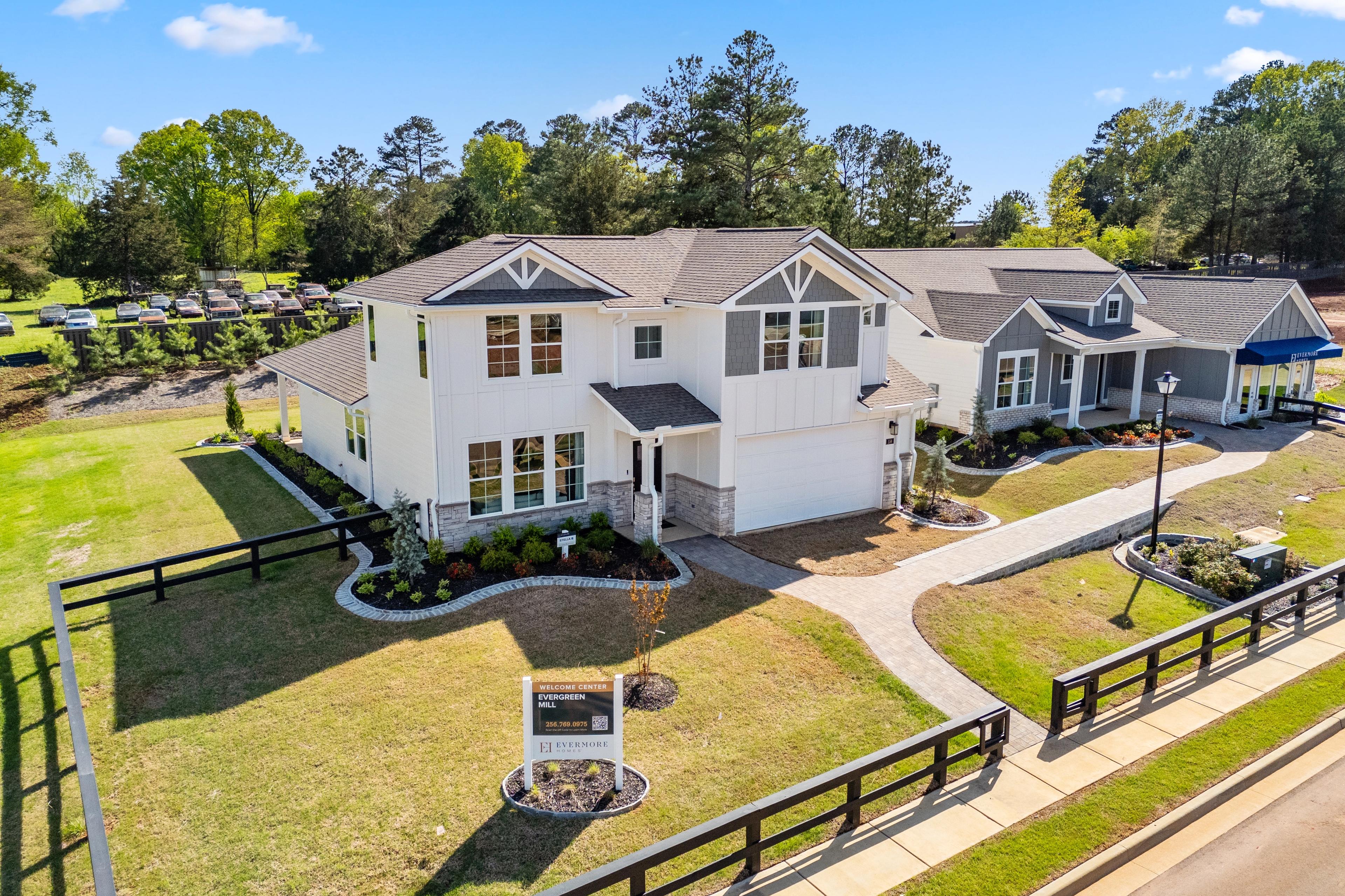 Aerial view of modern homes at Evergreen Mill in Madison Alabama featuring white and gray exteriors, gabled roofs, landscaped yards, and pine trees