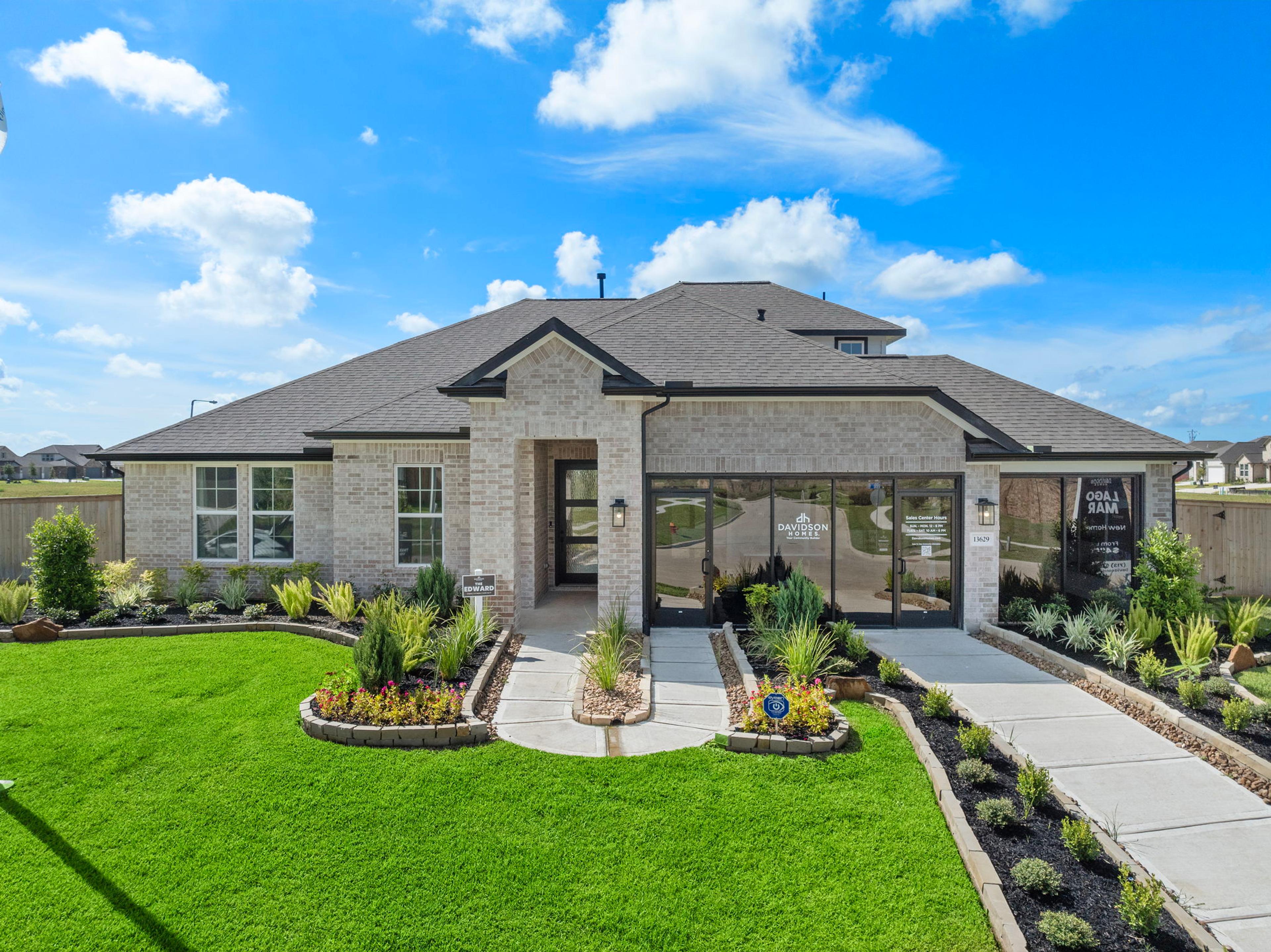 Modern brick ranch-style home exterior at Lago Mar in Texas City, Texas with covered porch, large windows, and lush landscaped yard