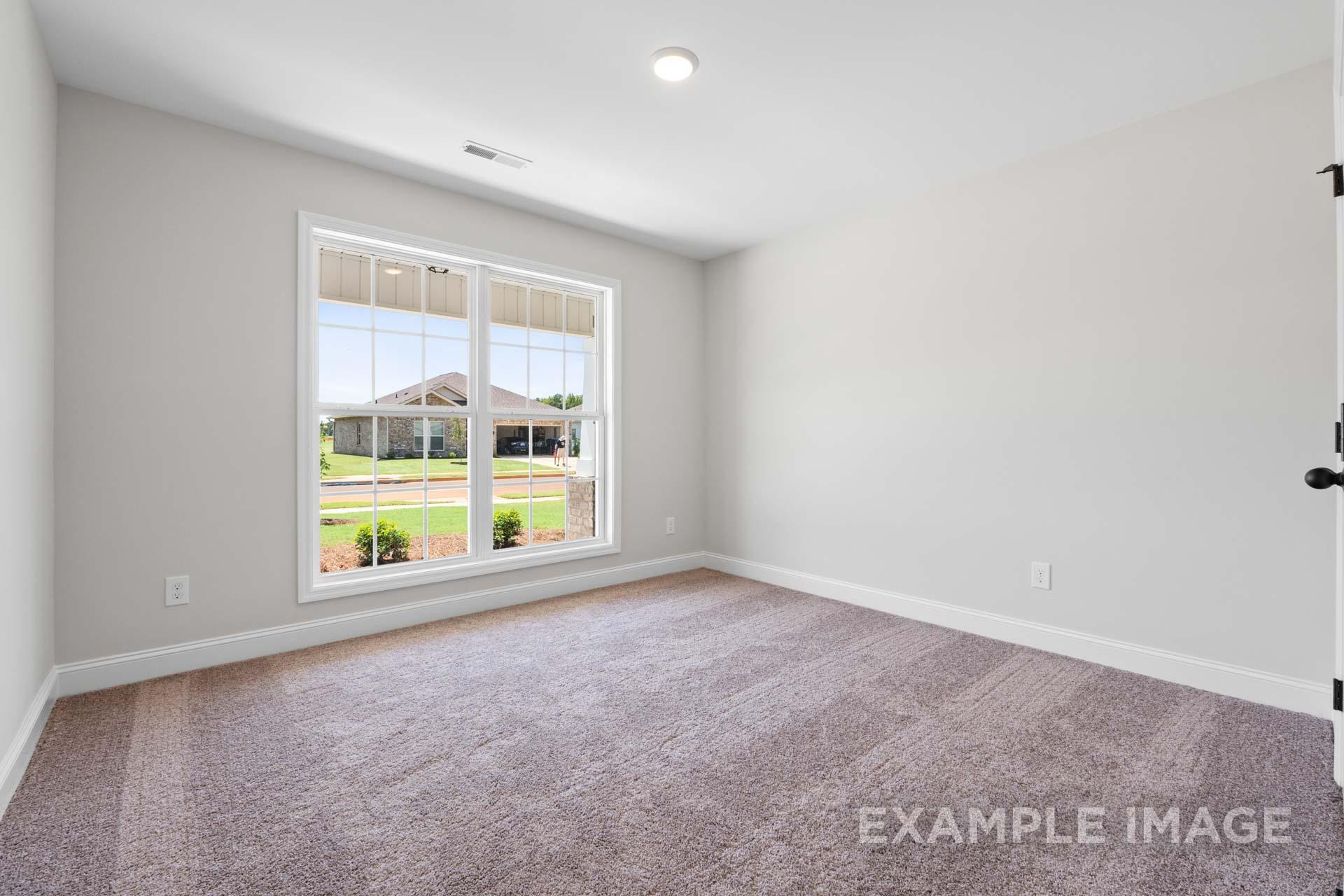 Spacious empty bedroom in The Holly M Davidson Homes design, gray walls, large window with backyard view, beige carpet
