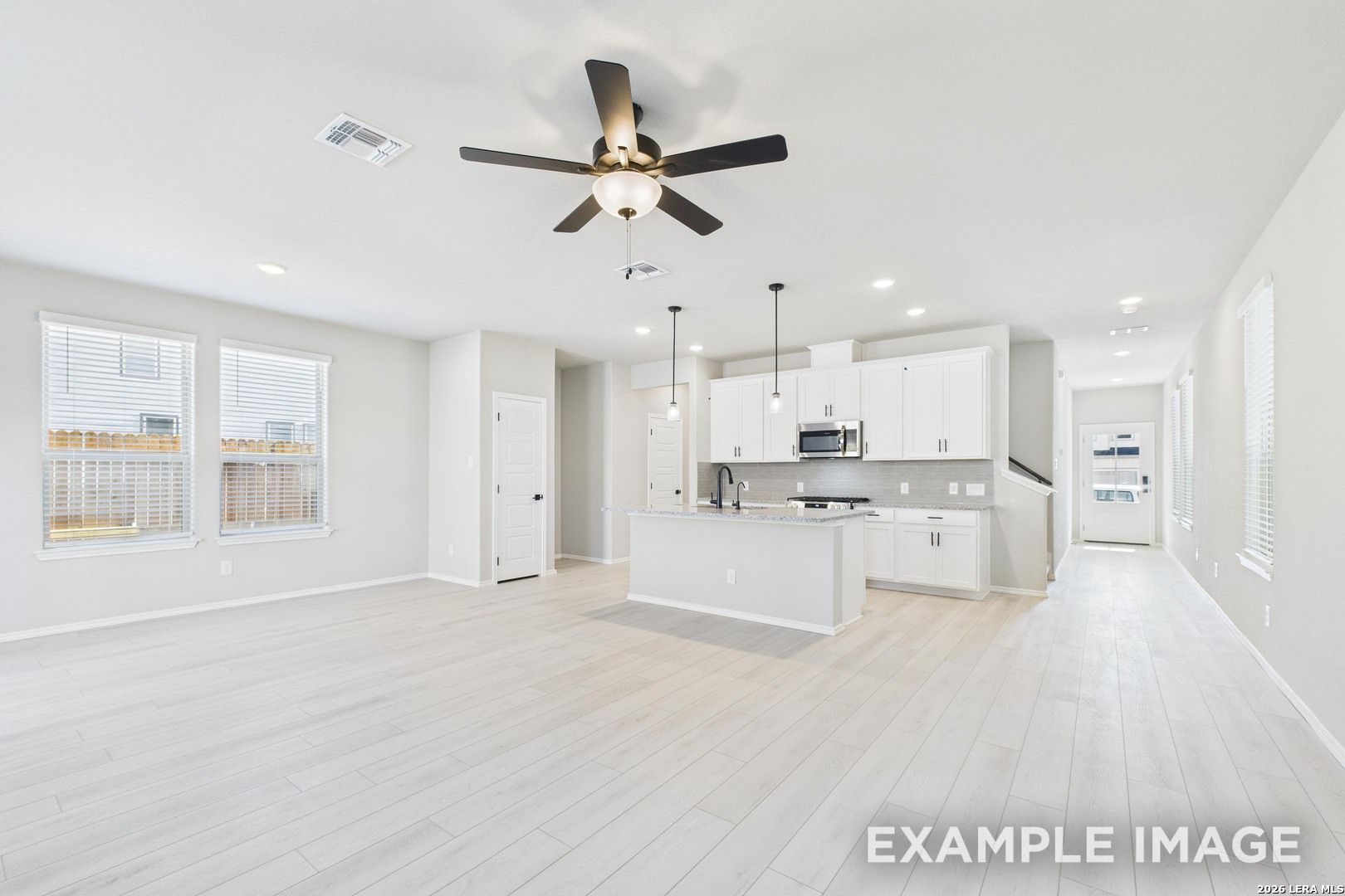 Open-concept kitchen with white cabinets and island in The Charlotte B floor plan by Davidson Homes, San Antonio, Texas.