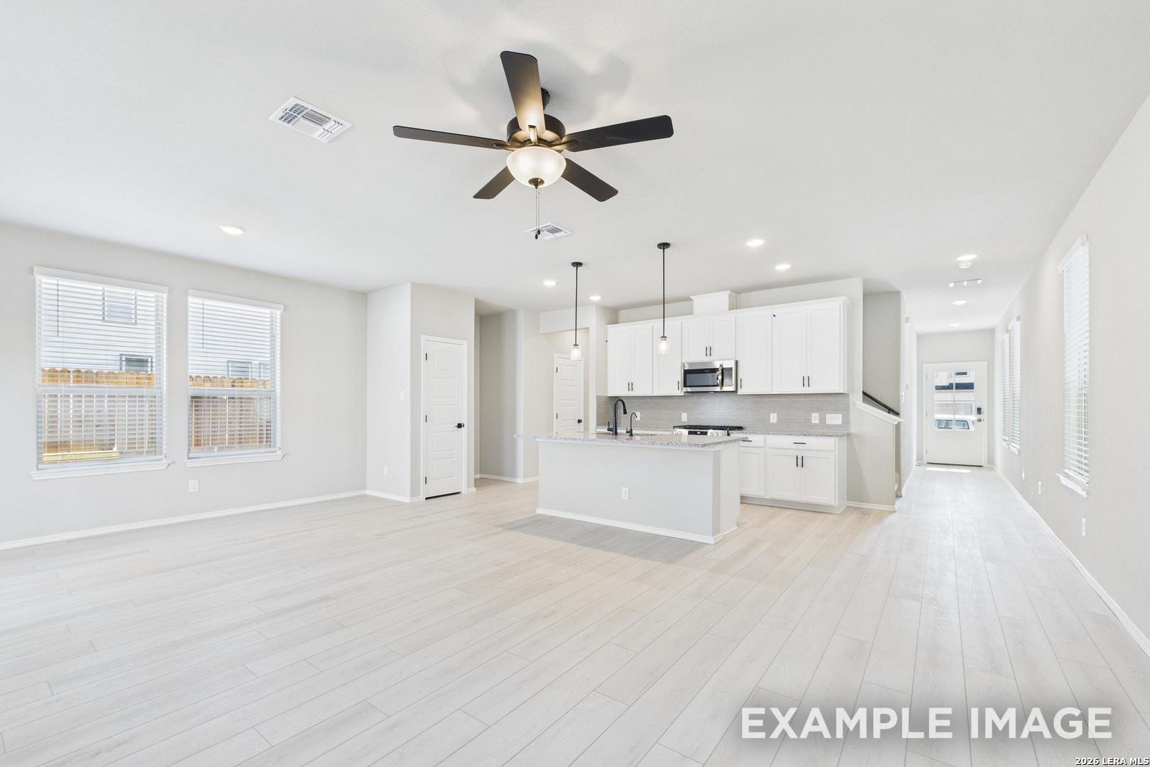 Open-concept kitchen with white cabinets and island in The Charlotte B floor plan by Davidson Homes, San Antonio, Texas.