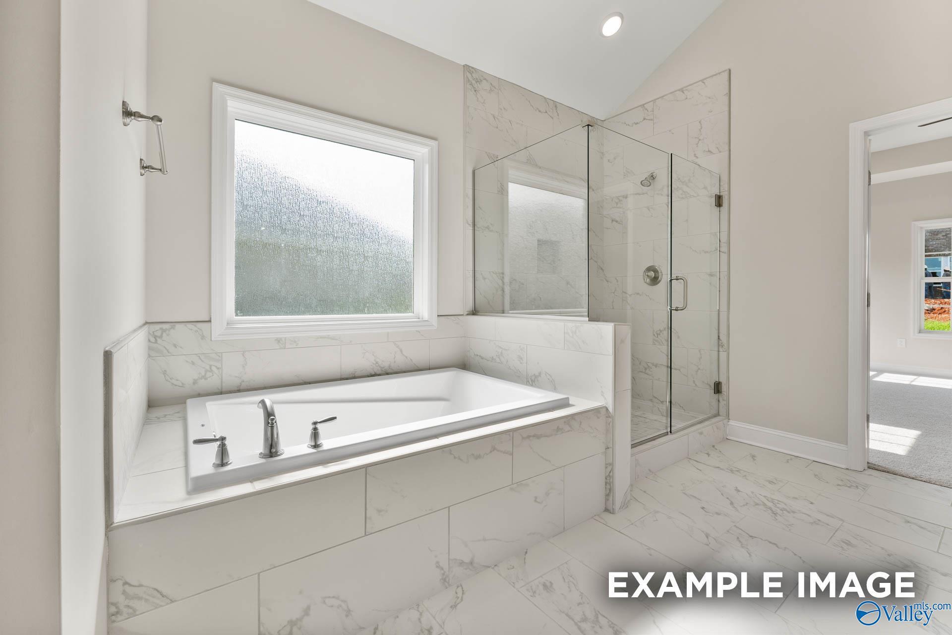 Luxurious master bathroom with freestanding soaking tub, glass shower, and white subway tiles in Davidson Homes The Finleigh, Huntsville, AL