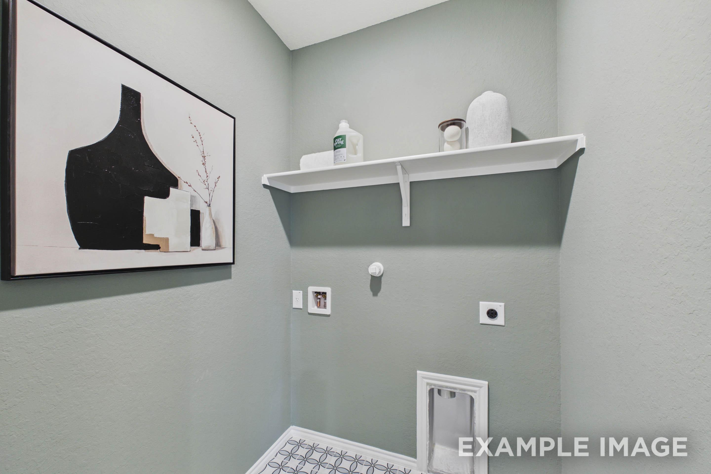 Functional laundry room in The Laurel G floor plan featuring sage green walls, wall-mounted shelving, and patterned tile.