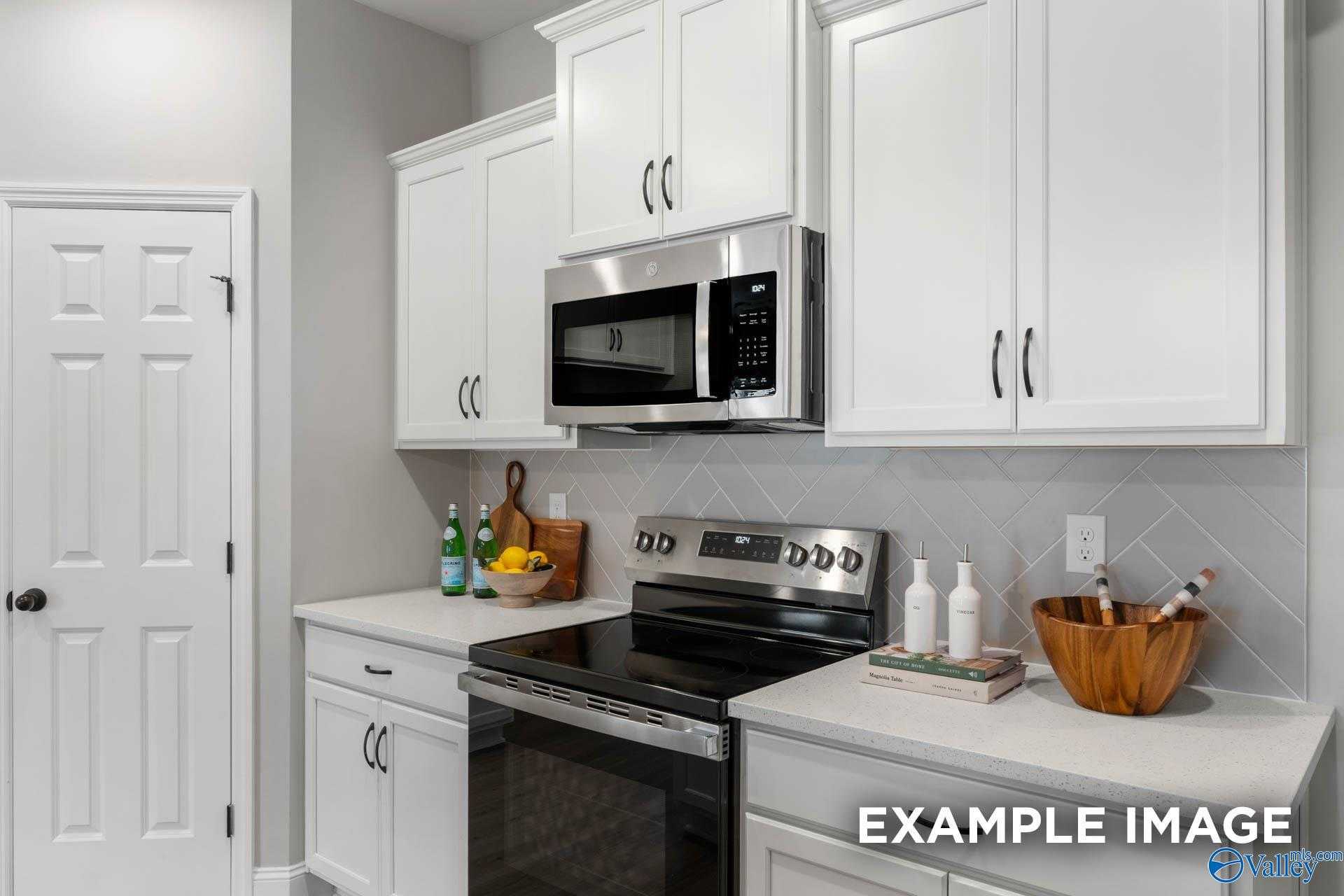 Modern kitchen with white shaker cabinets, stainless steel range and microwave, quartz counters in Davidson Homes The Daphne C, Owens Cross Roads, Alabama
