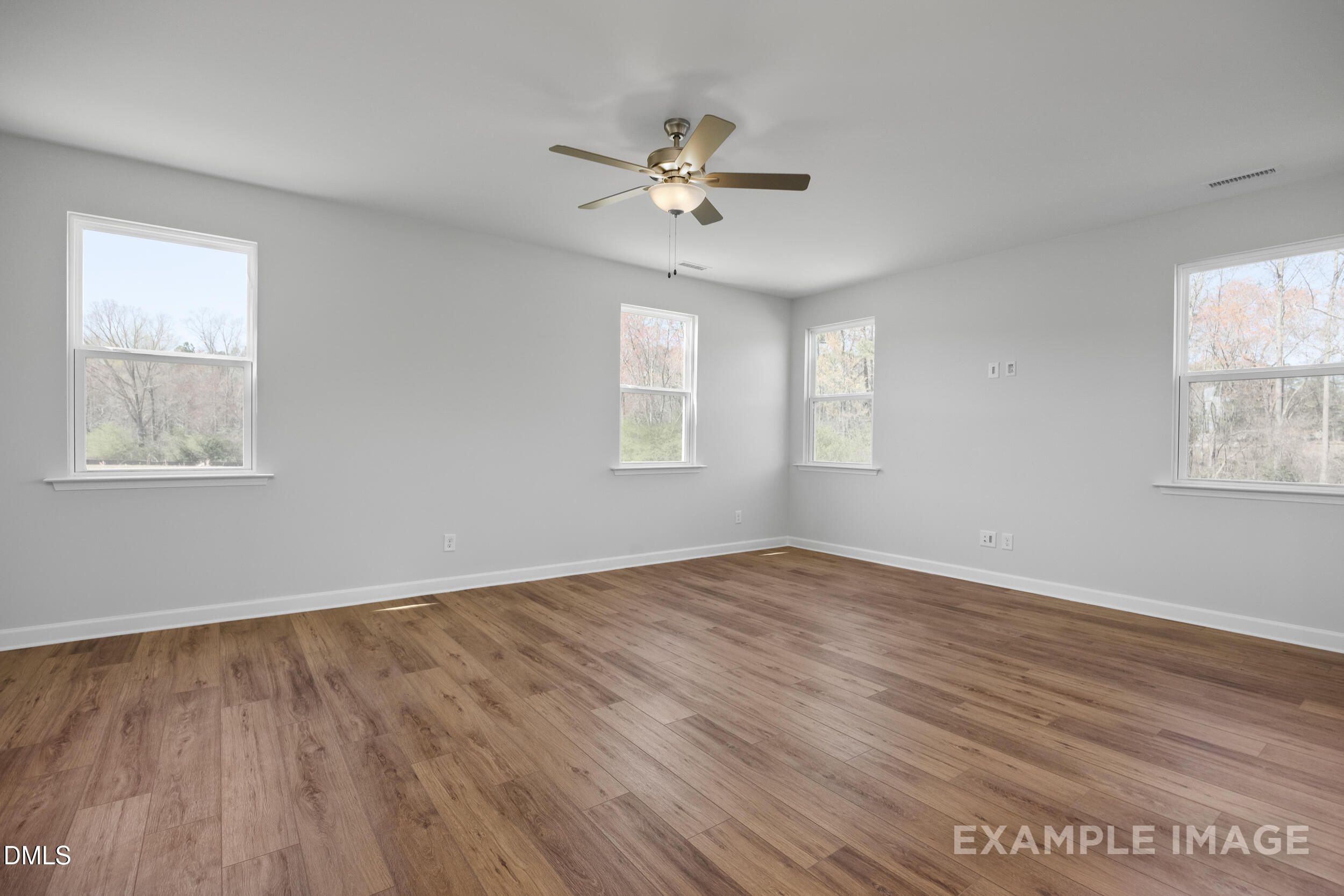 Spacious bedroom with wood-look flooring and ceiling fan in The Gavin A floor plan at Gregory Village, Lillington, NC.