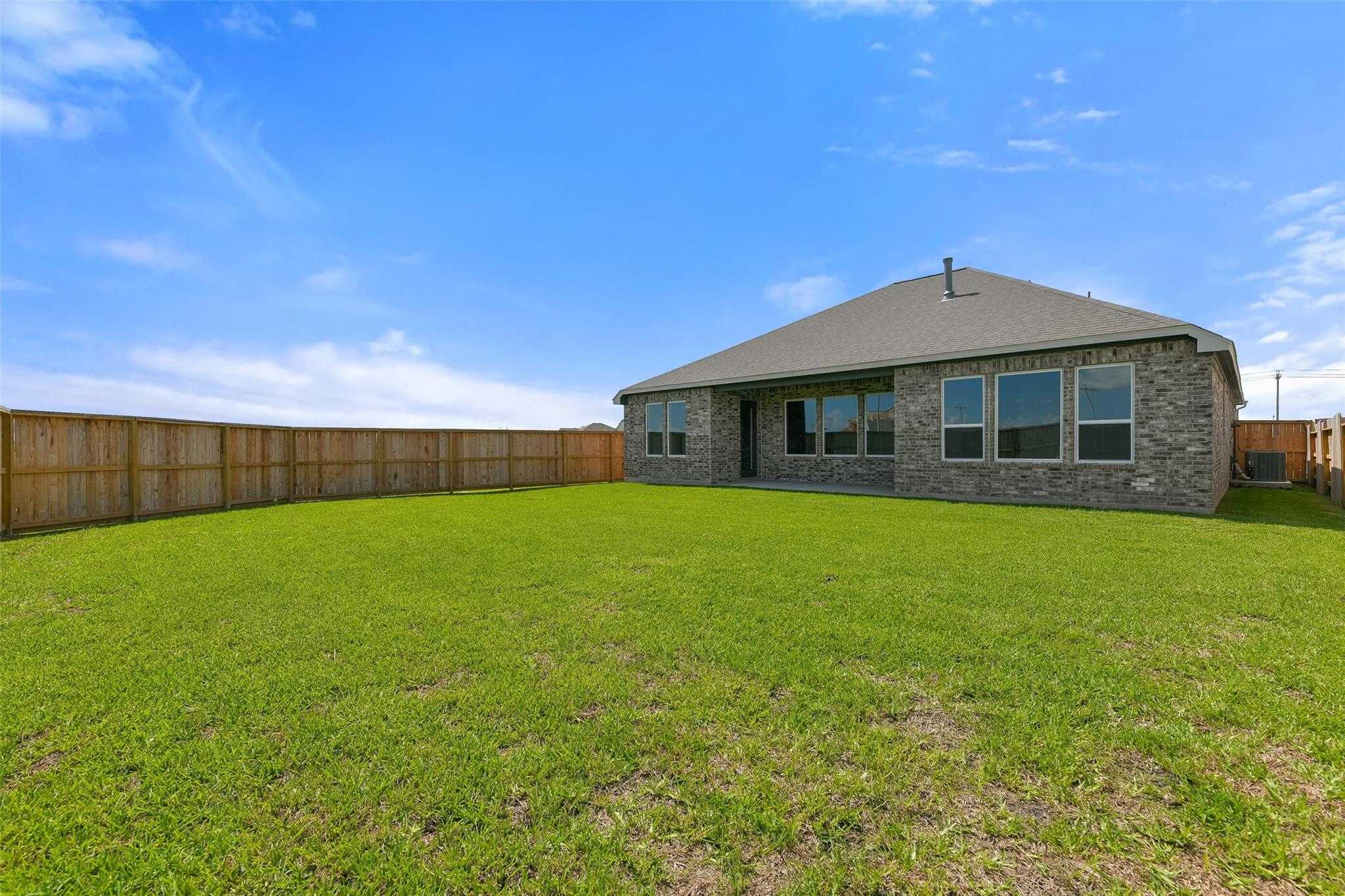 Spacious backyard with covered patio, large windows, and green lawn in Davidson Homes The Edward A, Lago Mar, Texas City
