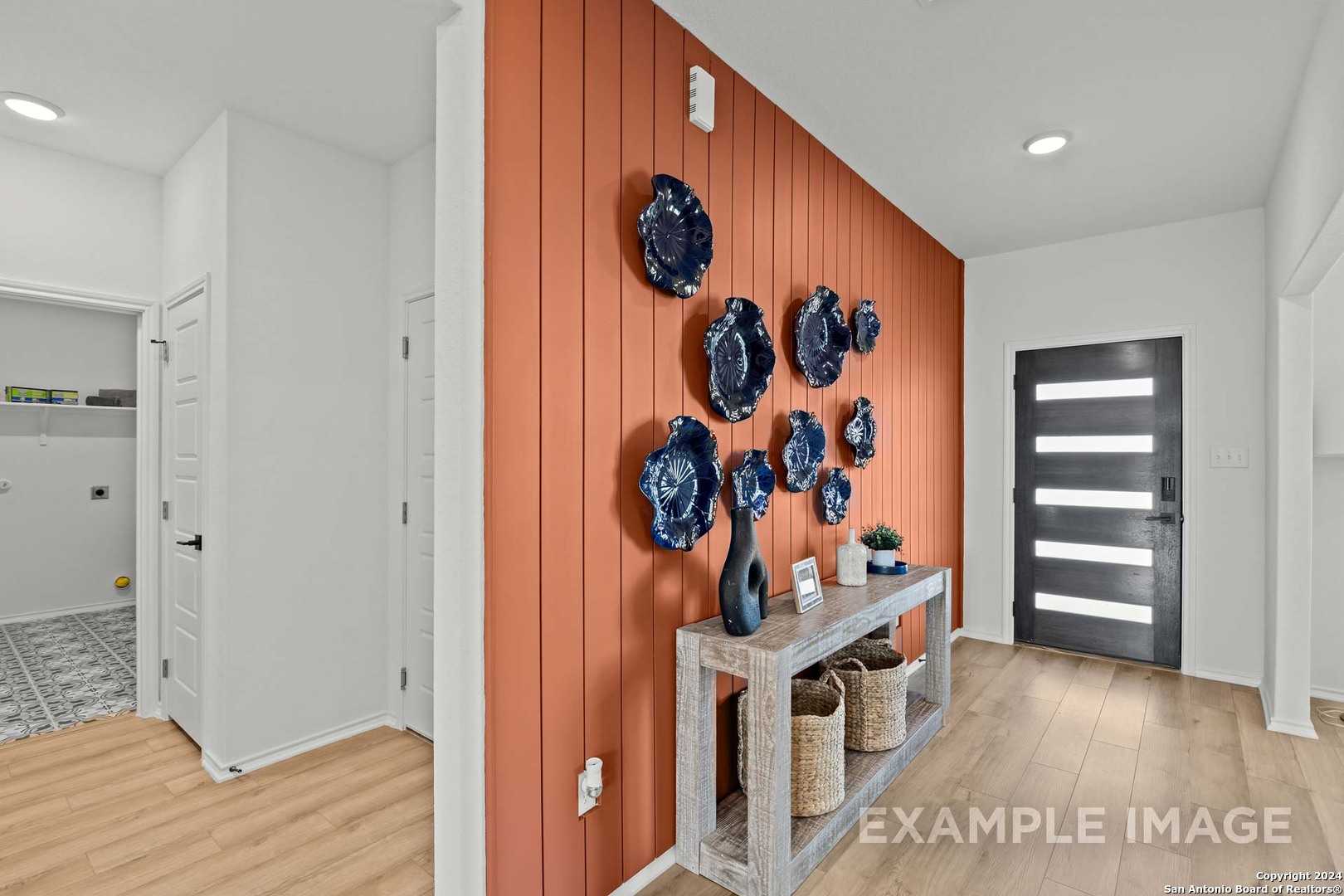 Stylish entryway featuring terracotta accent wall with blue plate decor and console table in Davidson Homes The Douglas G, Bricewood, San Antonio